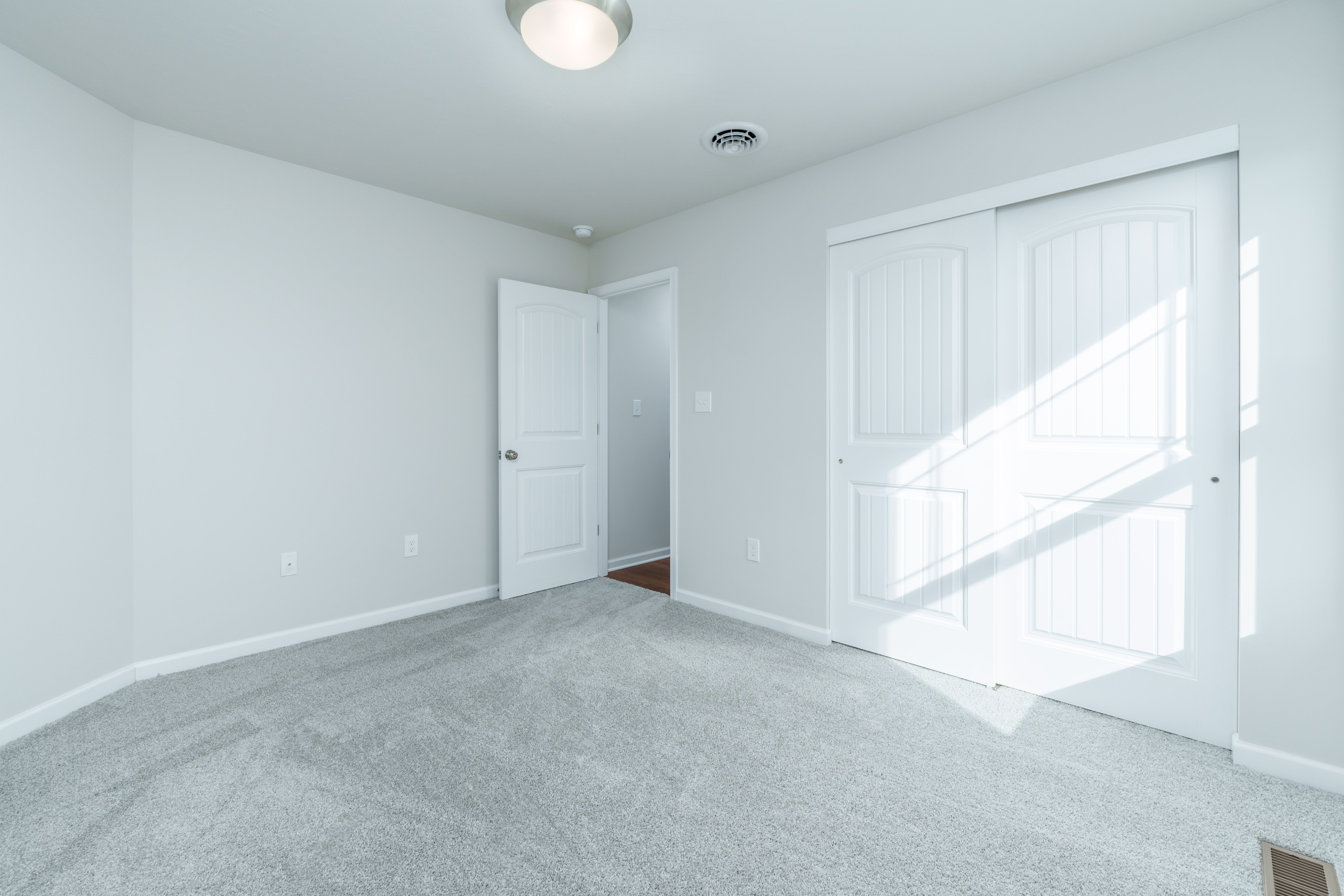 Bedroom with plush carpet, double closet doors, and open entry to hallway