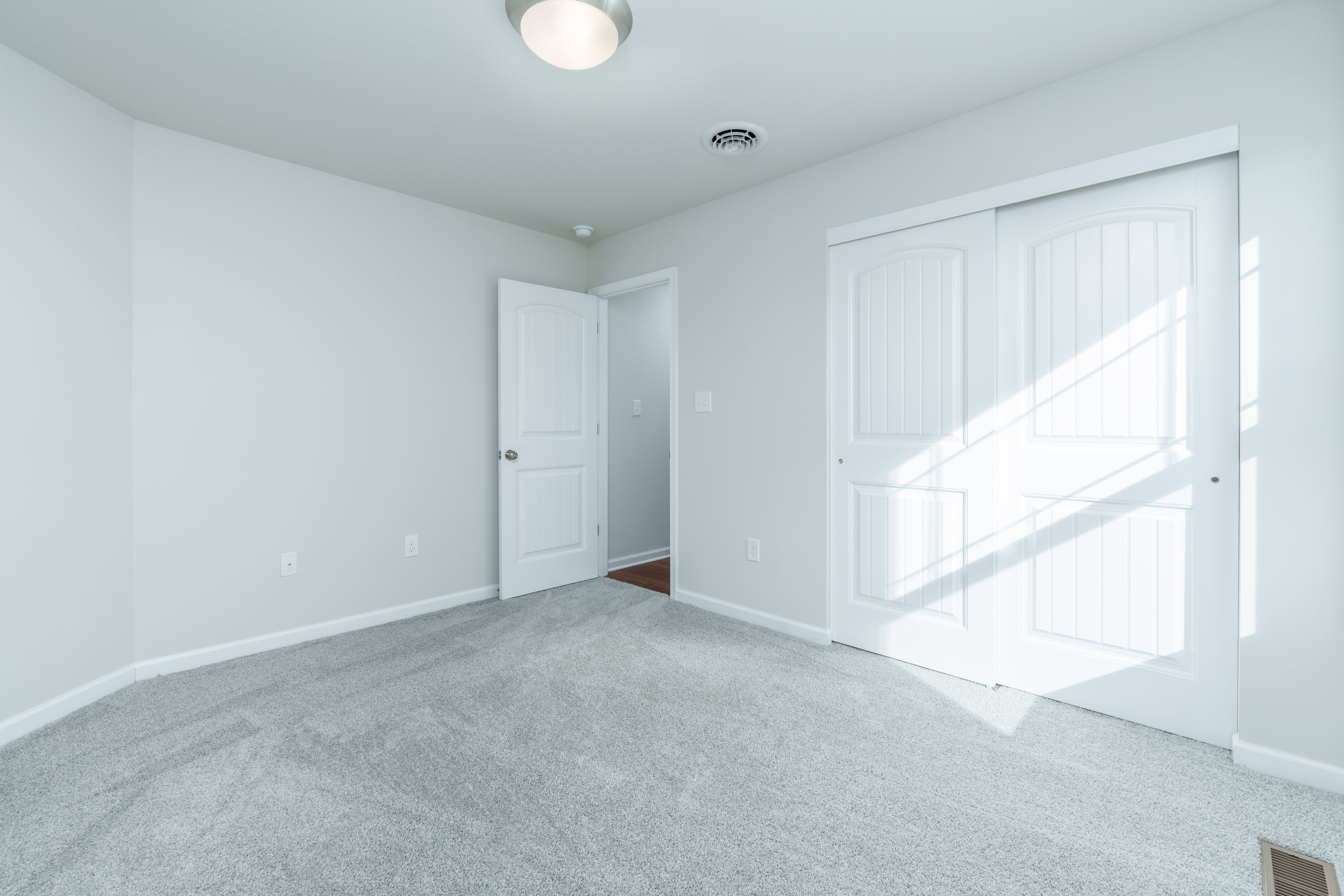 Bedroom with plush carpet, double closet doors, and open entry to hallway