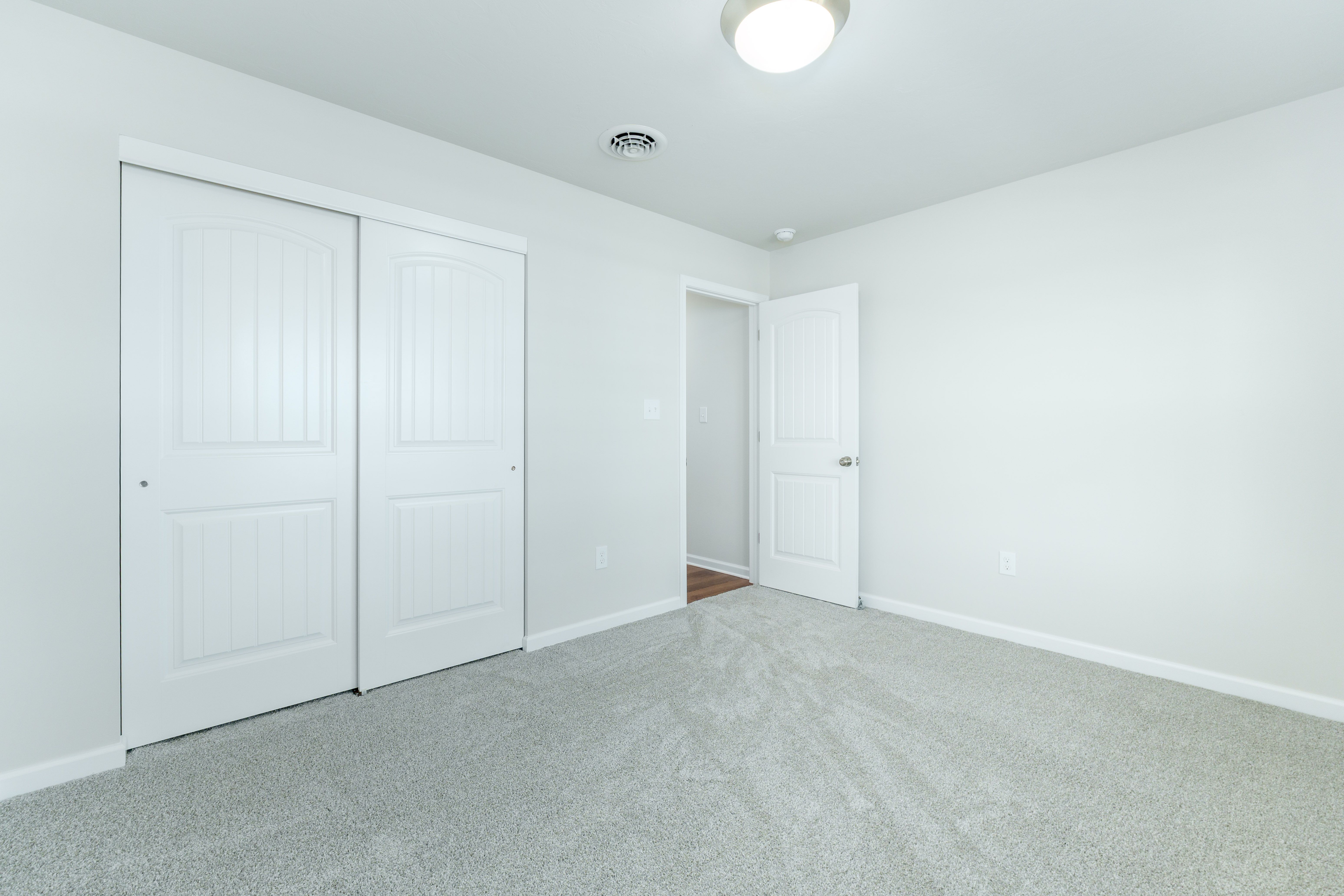 Bedroom with soft carpet, double closet doors, and white trim throughout