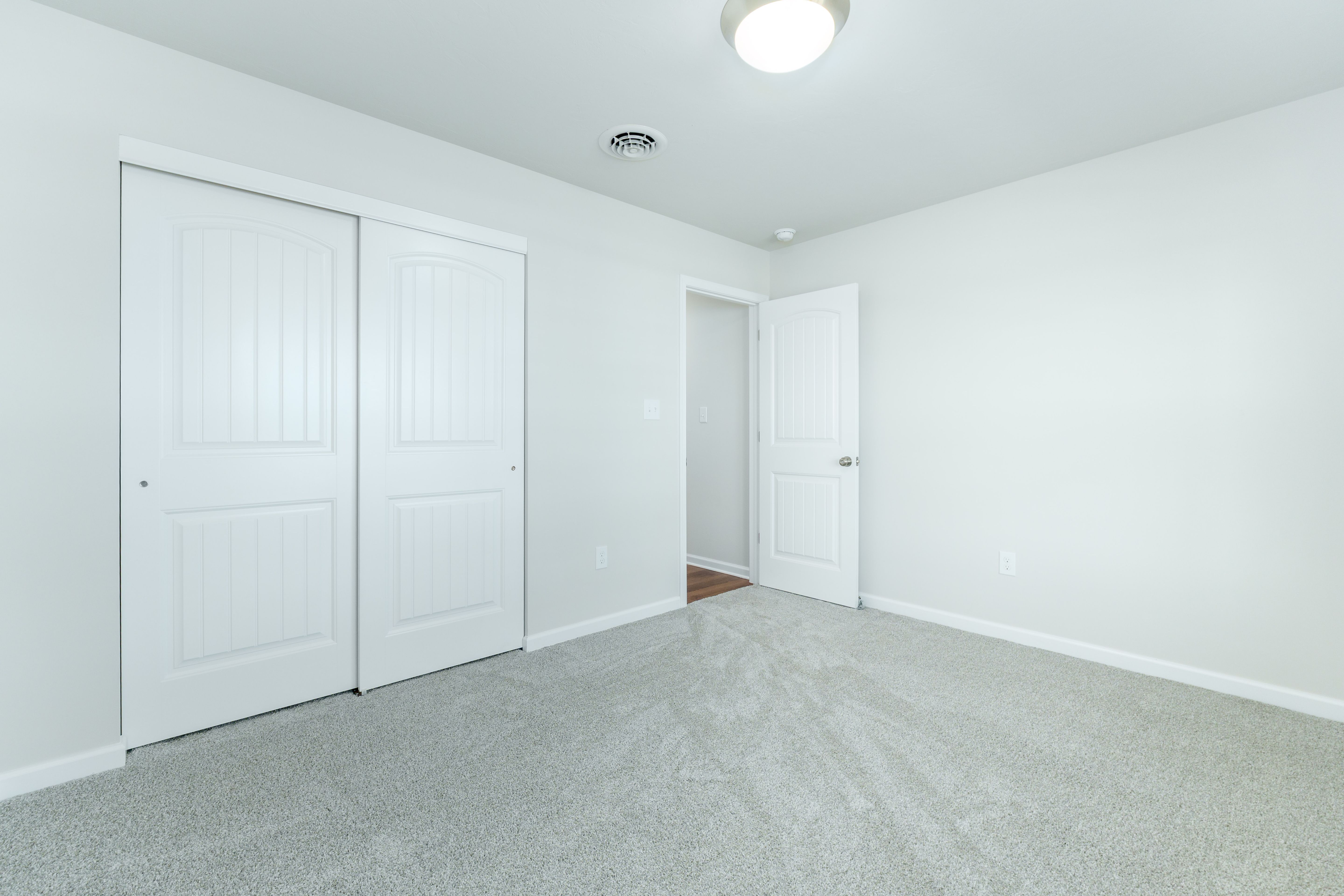 Bedroom with soft carpet, double closet doors, and white trim throughout