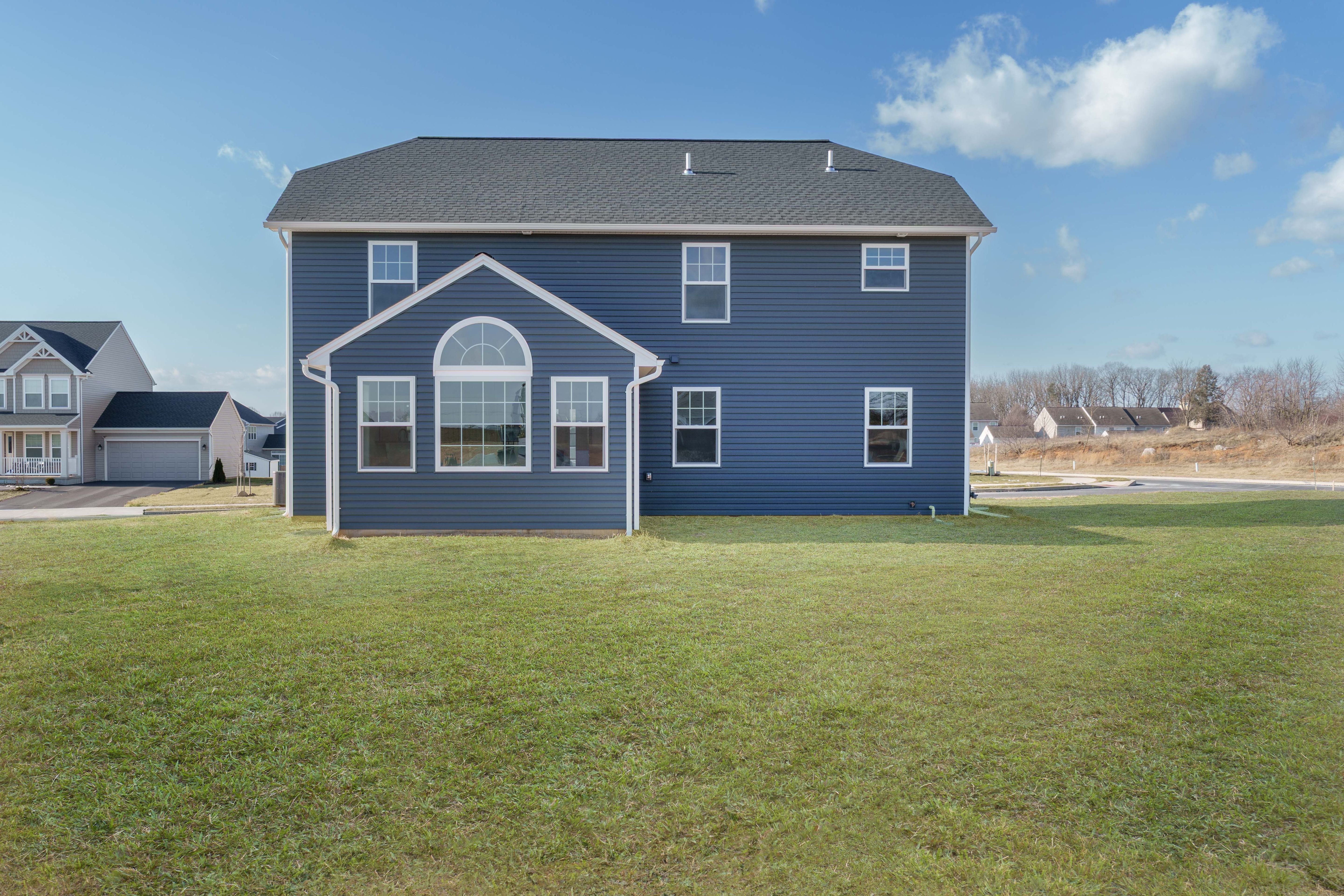 Two-story blue home with stone accents, white trim, covered front porch, and two-car garage