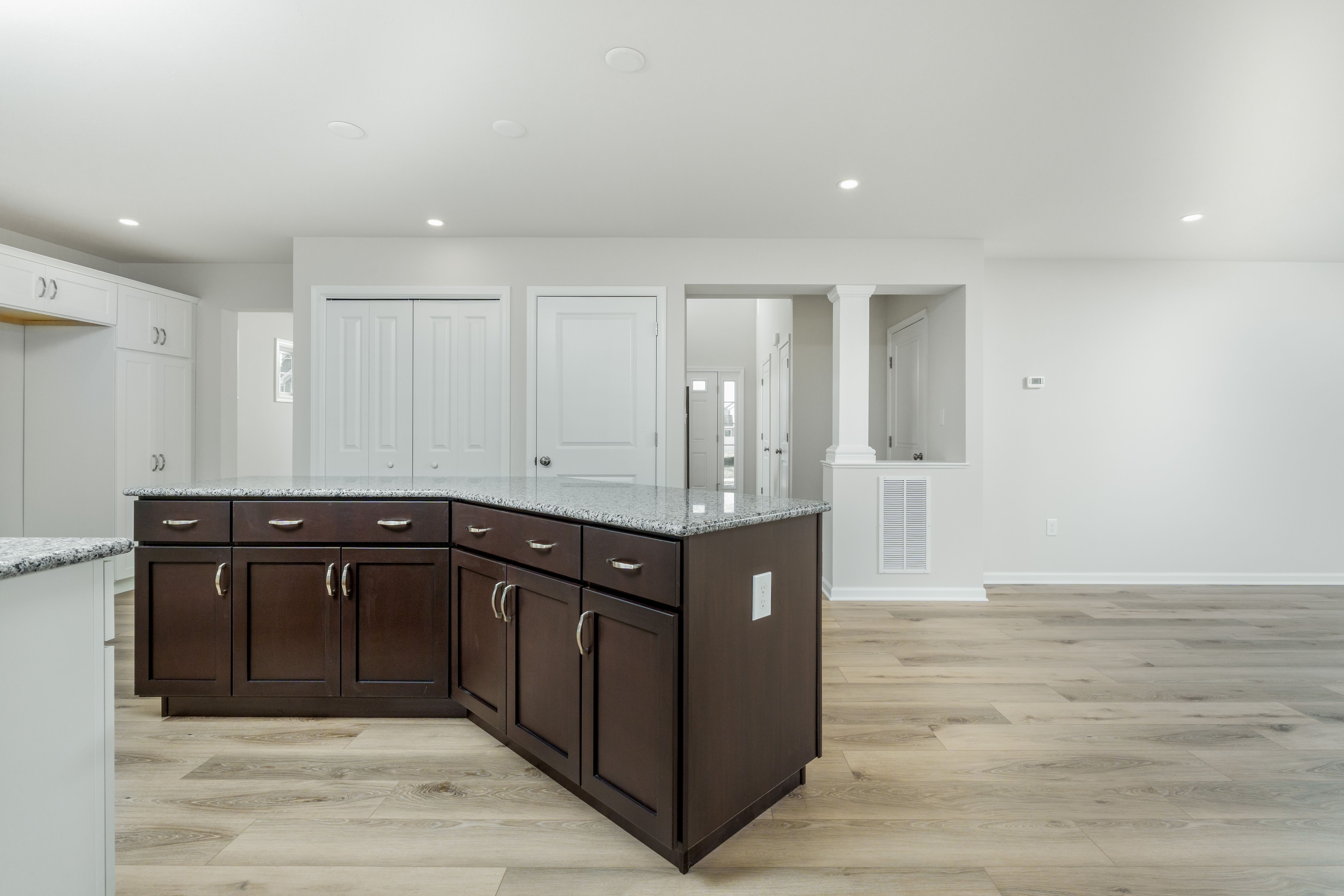 Kitchen with large island, dark wood cabinets, granite countertops, recessed lighting, and open layout.