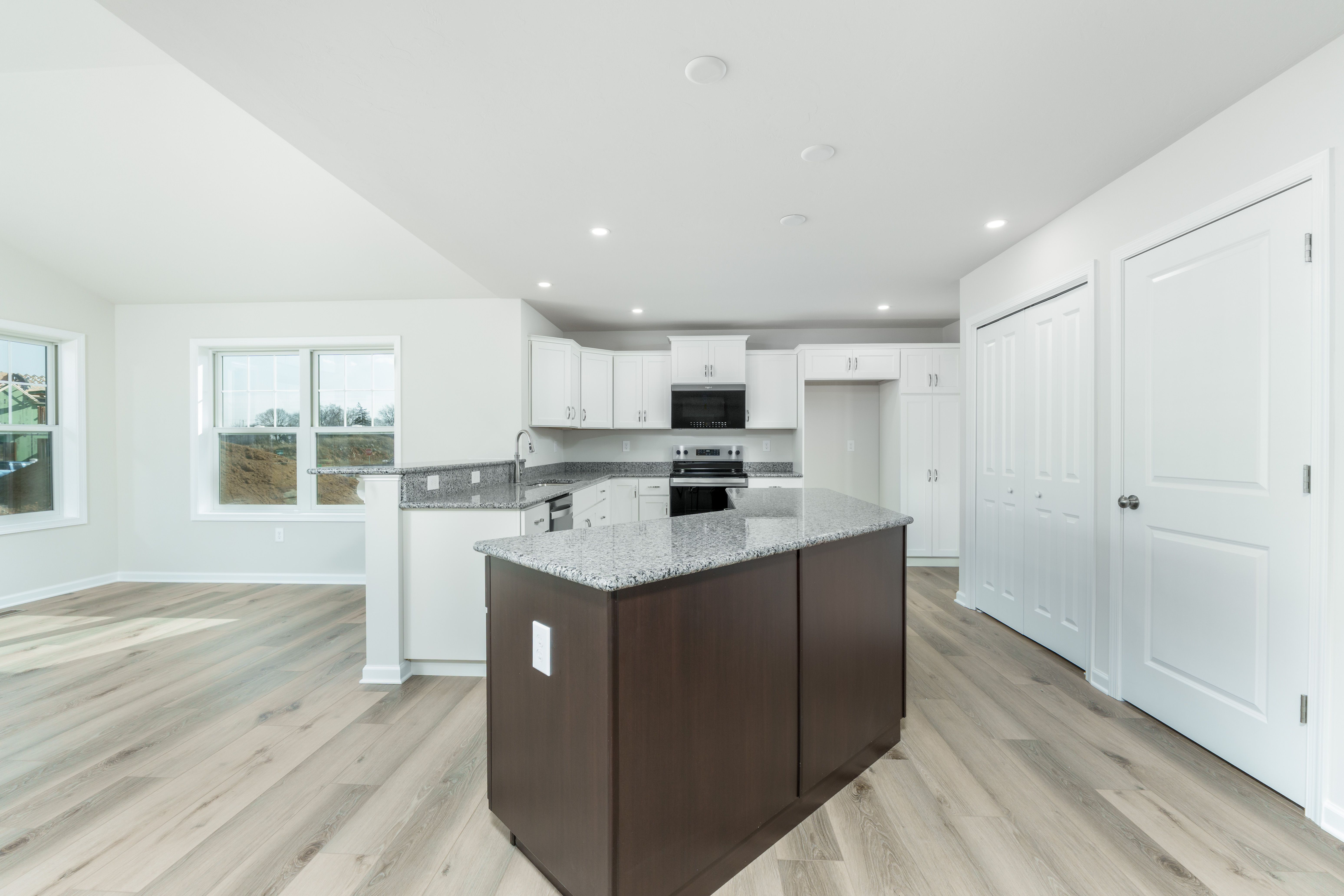 Spacious kitchen featuring large island, granite countertops, recessed lighting, and open sightline to morning room.