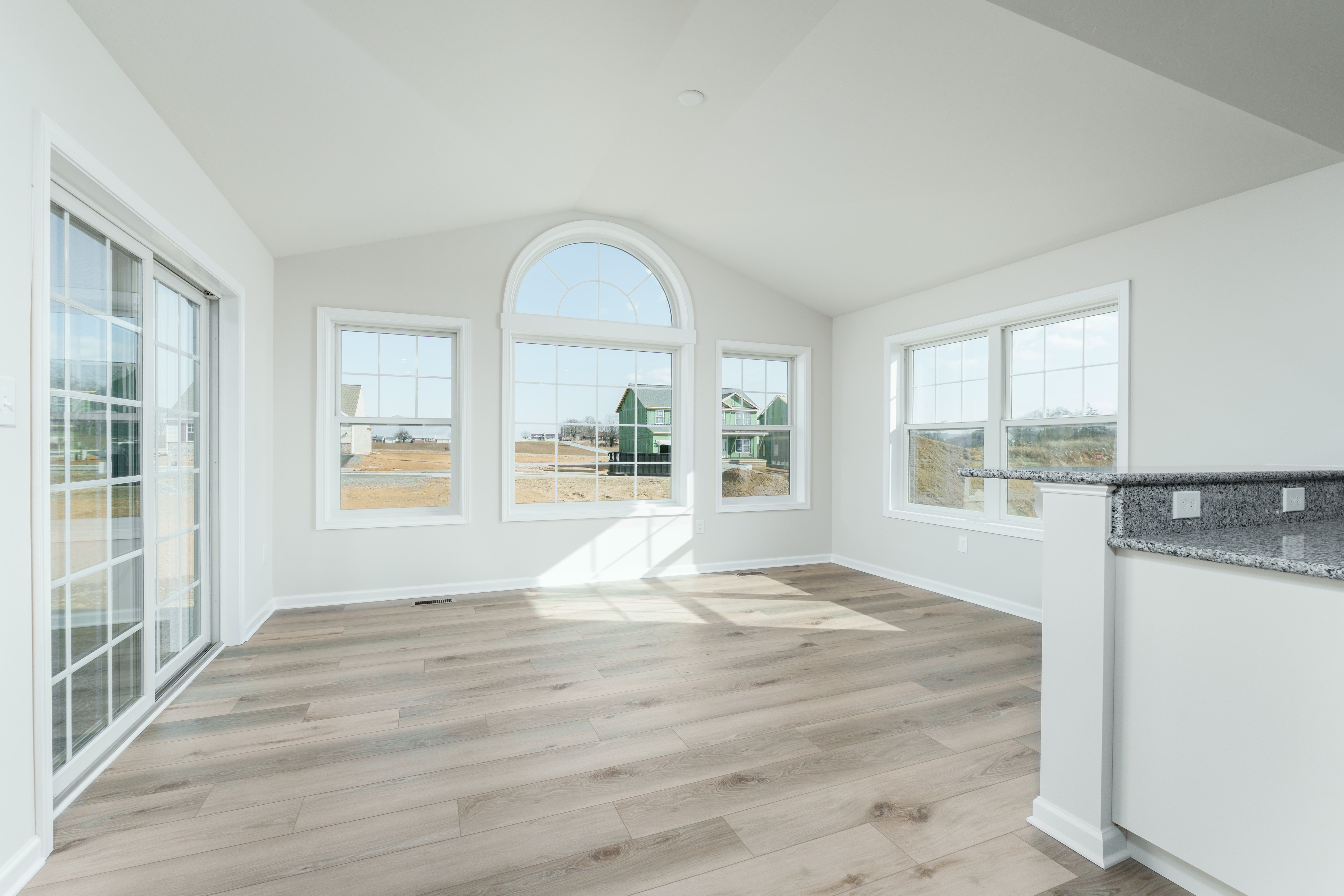 Bright morning room with arched window, multiple tall windows, and luxury vinyl plank flooring.