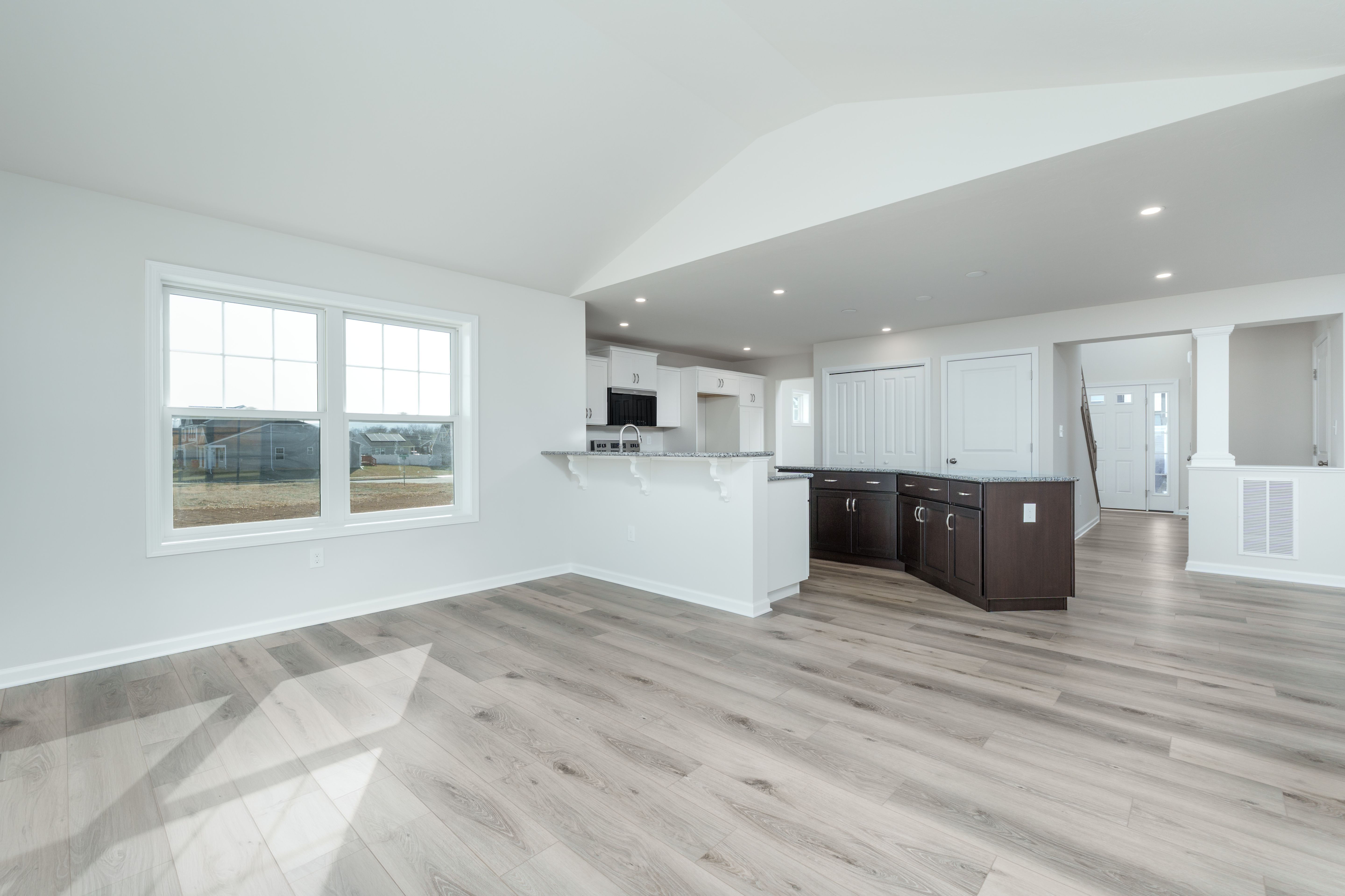 Sunlit morning room with arched window, three tall windows, and luxury vinyl plank flooring.