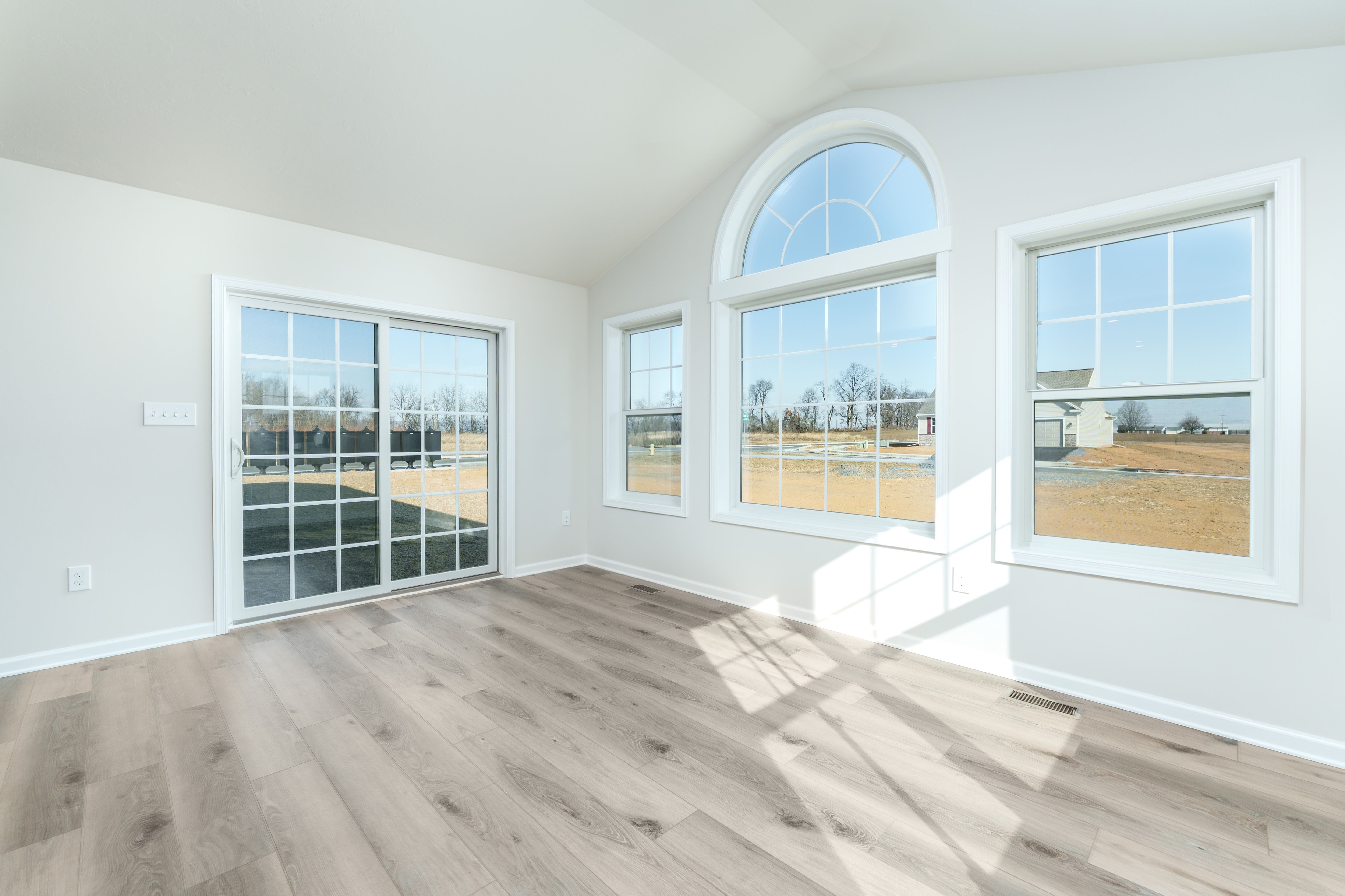 Open morning room with sliding glass door, double windows, and luxury vinyl plank flooring.