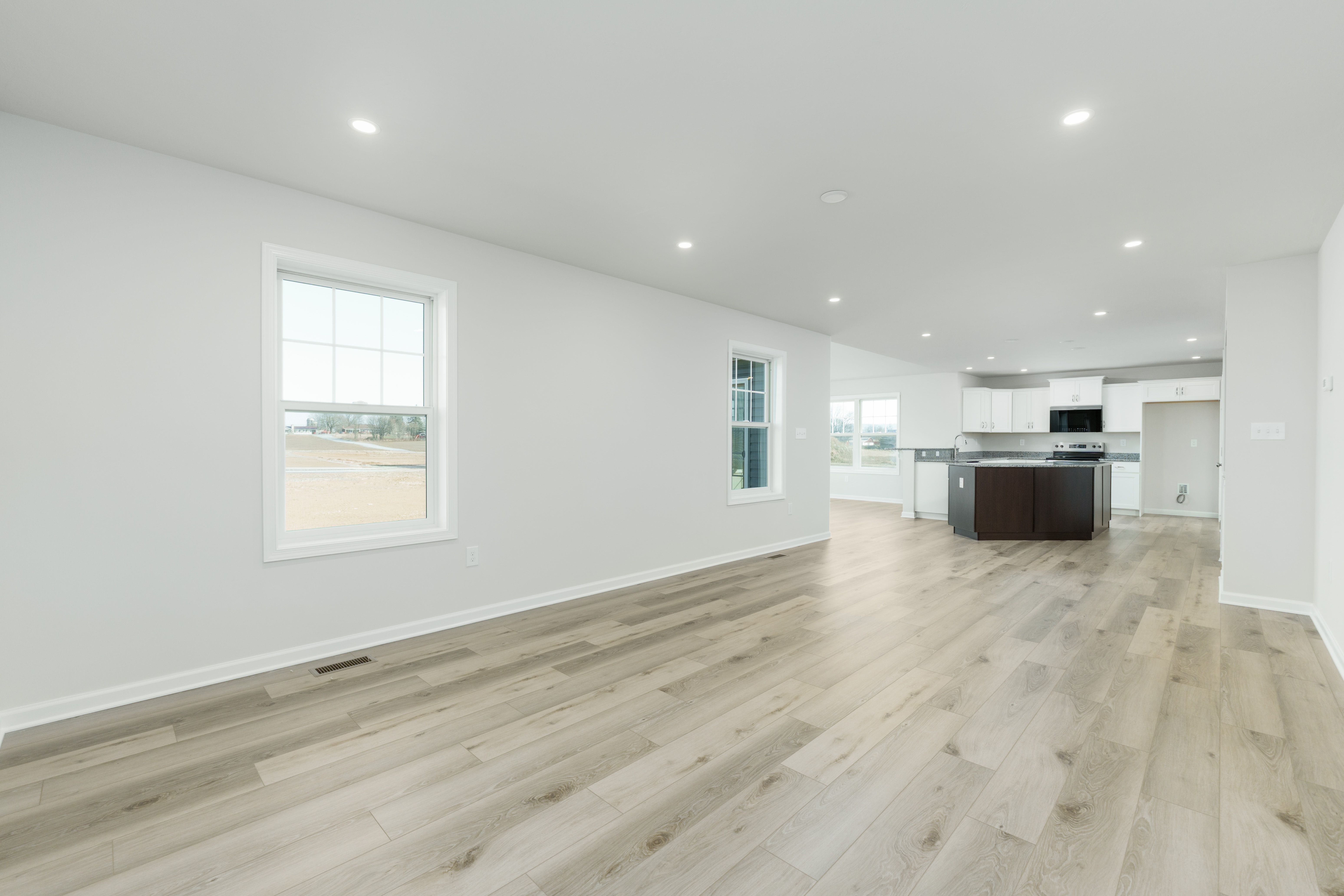 Spacious family room with luxury vinyl plank flooring, recessed lighting, and open layout to kitchen.