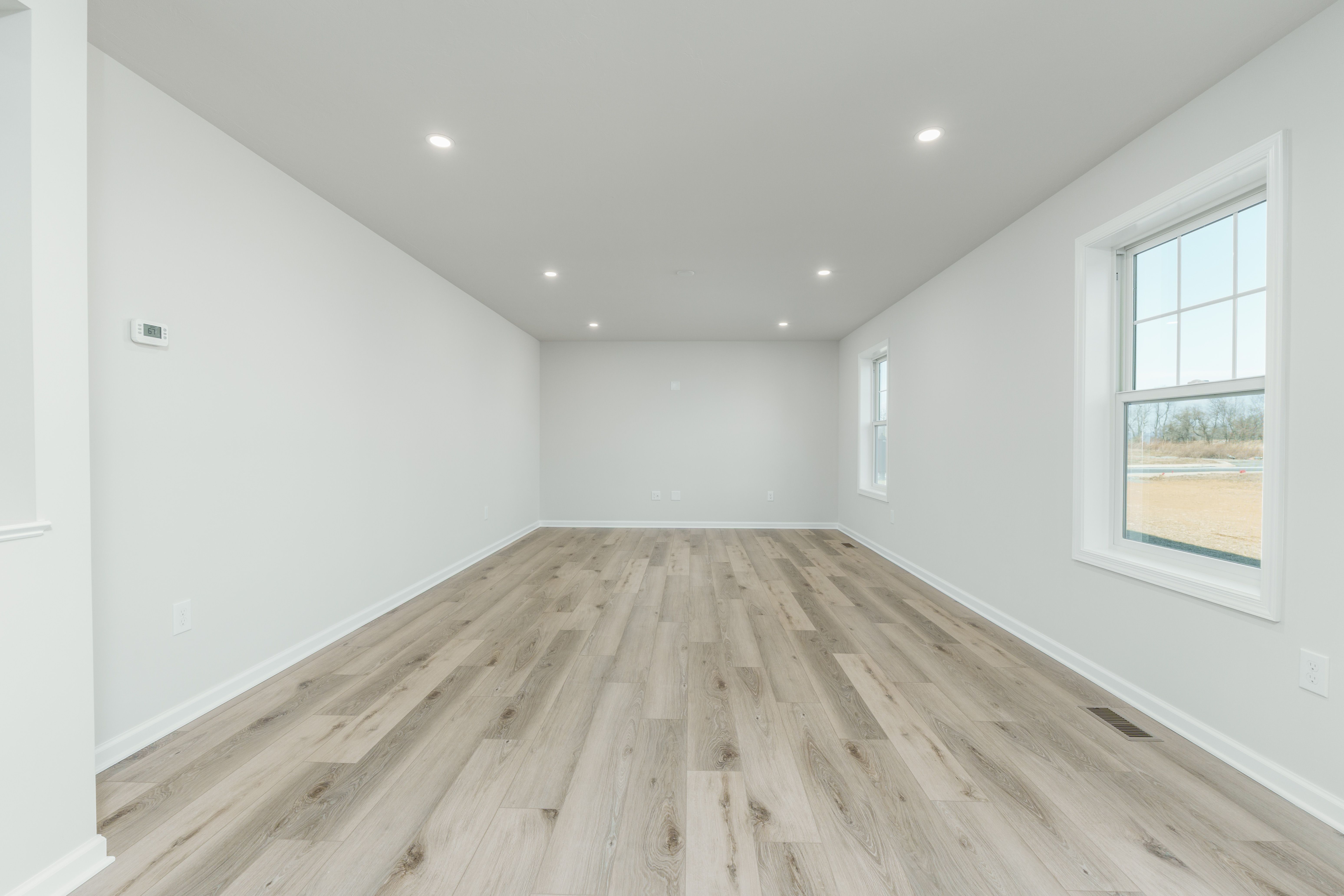 Open family room with large windows, recessed lights, and seamless flow into kitchen with island.