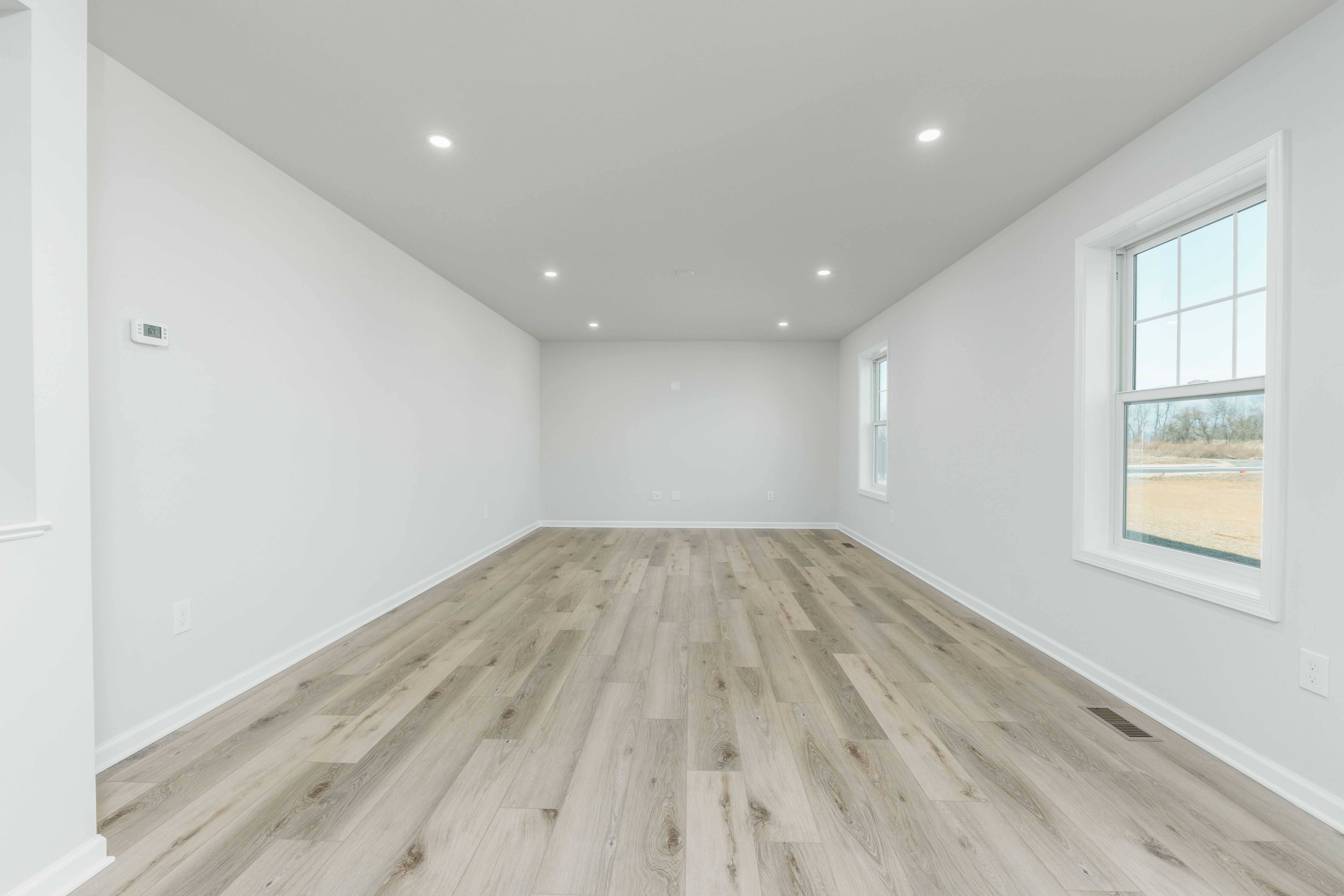 Open family room with large windows, recessed lights, and seamless flow into kitchen with island.