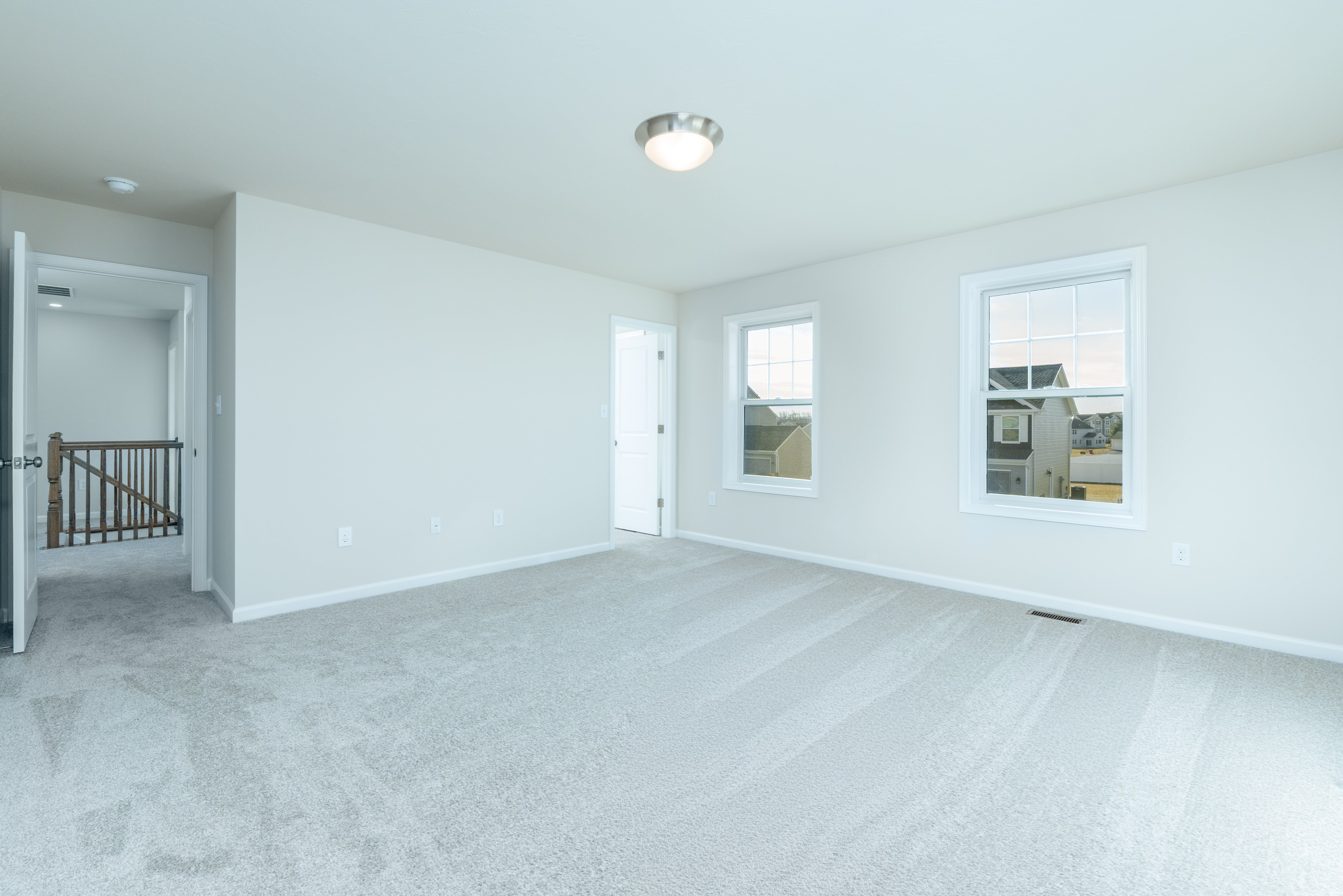 Large owners bedroom with soft carpet, neutral walls, and flush mount ceiling light.