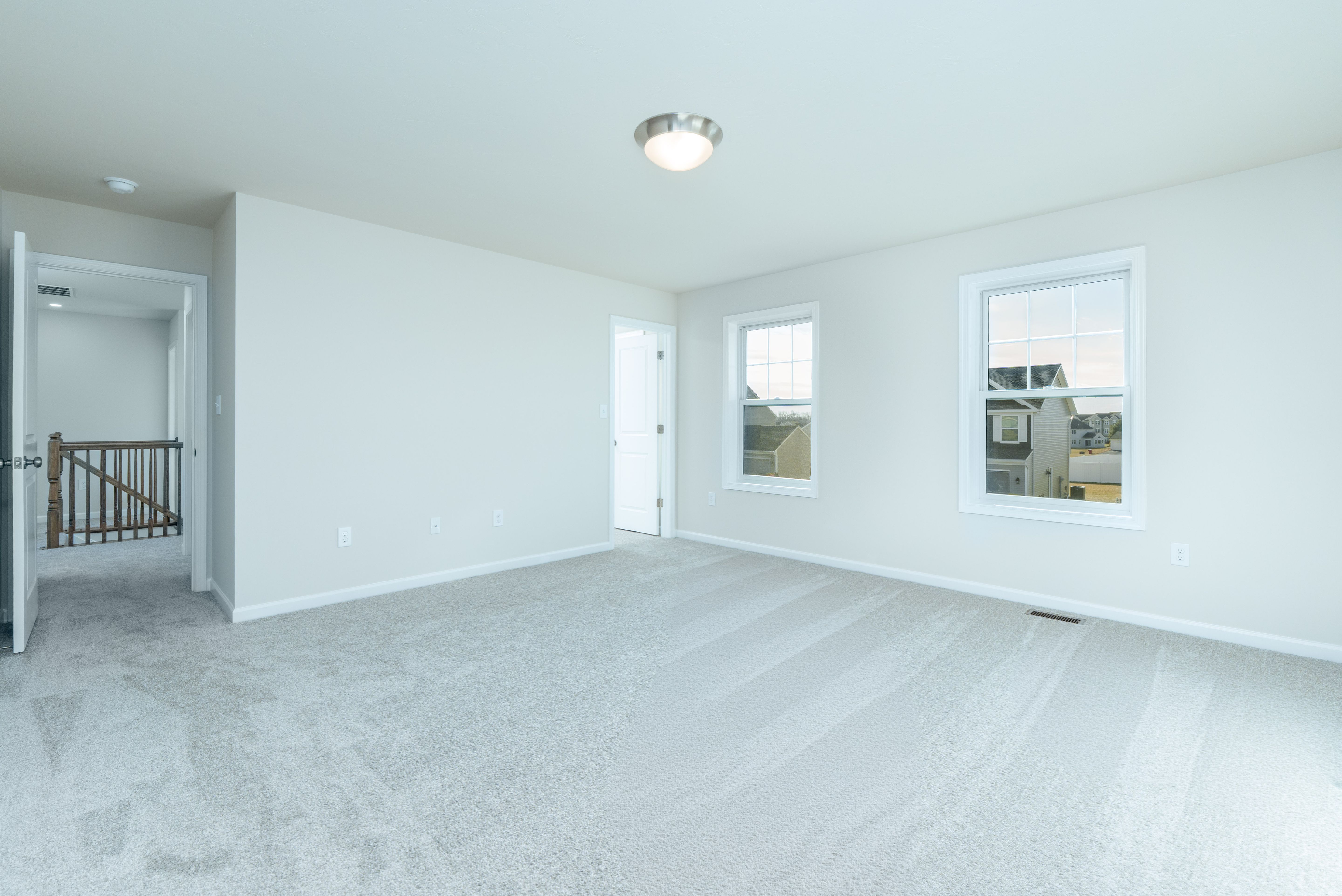 Large owners bedroom with soft carpet, neutral walls, and flush mount ceiling light.