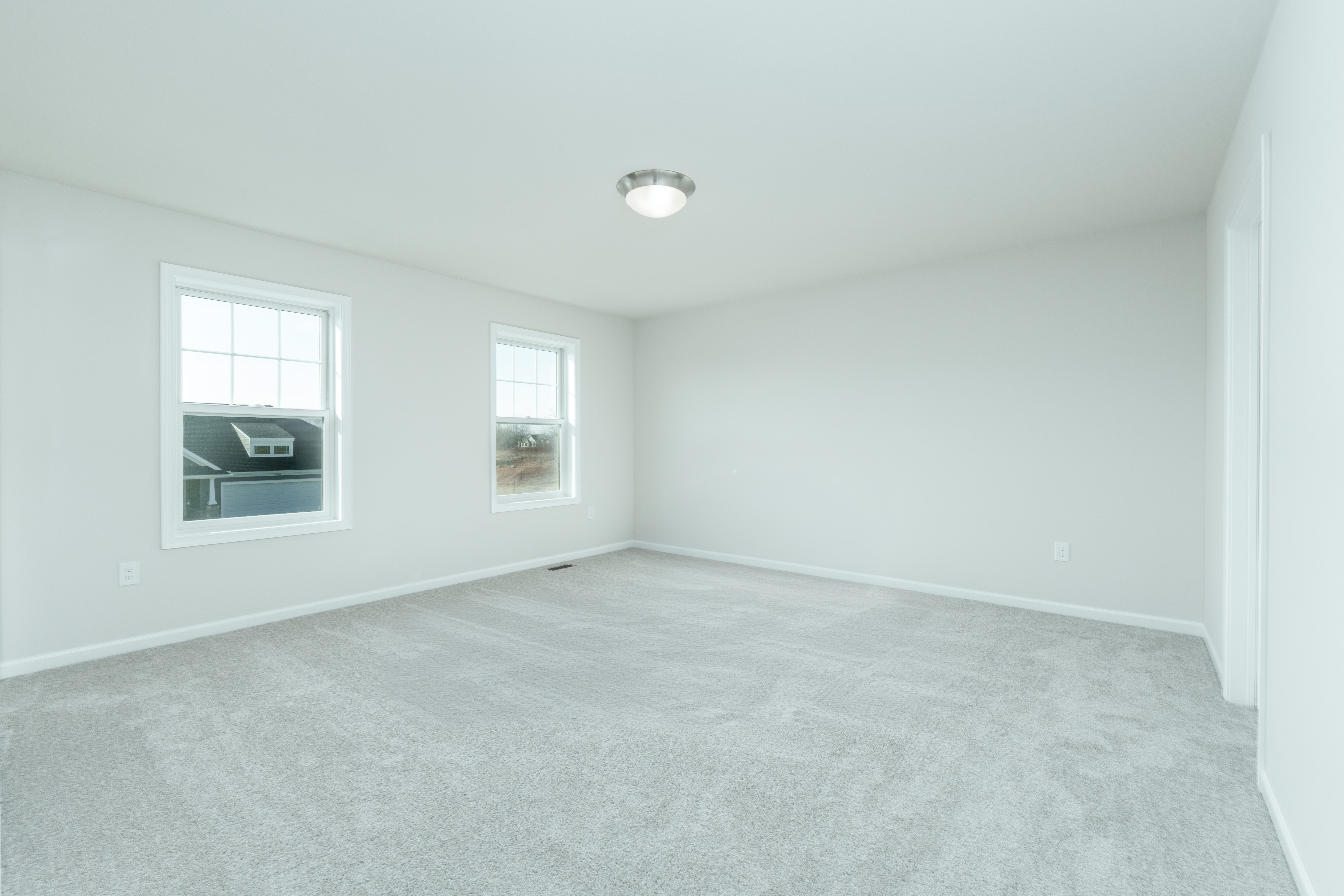 Spacious owners bedroom with soft carpet, double windows, and neutral walls.