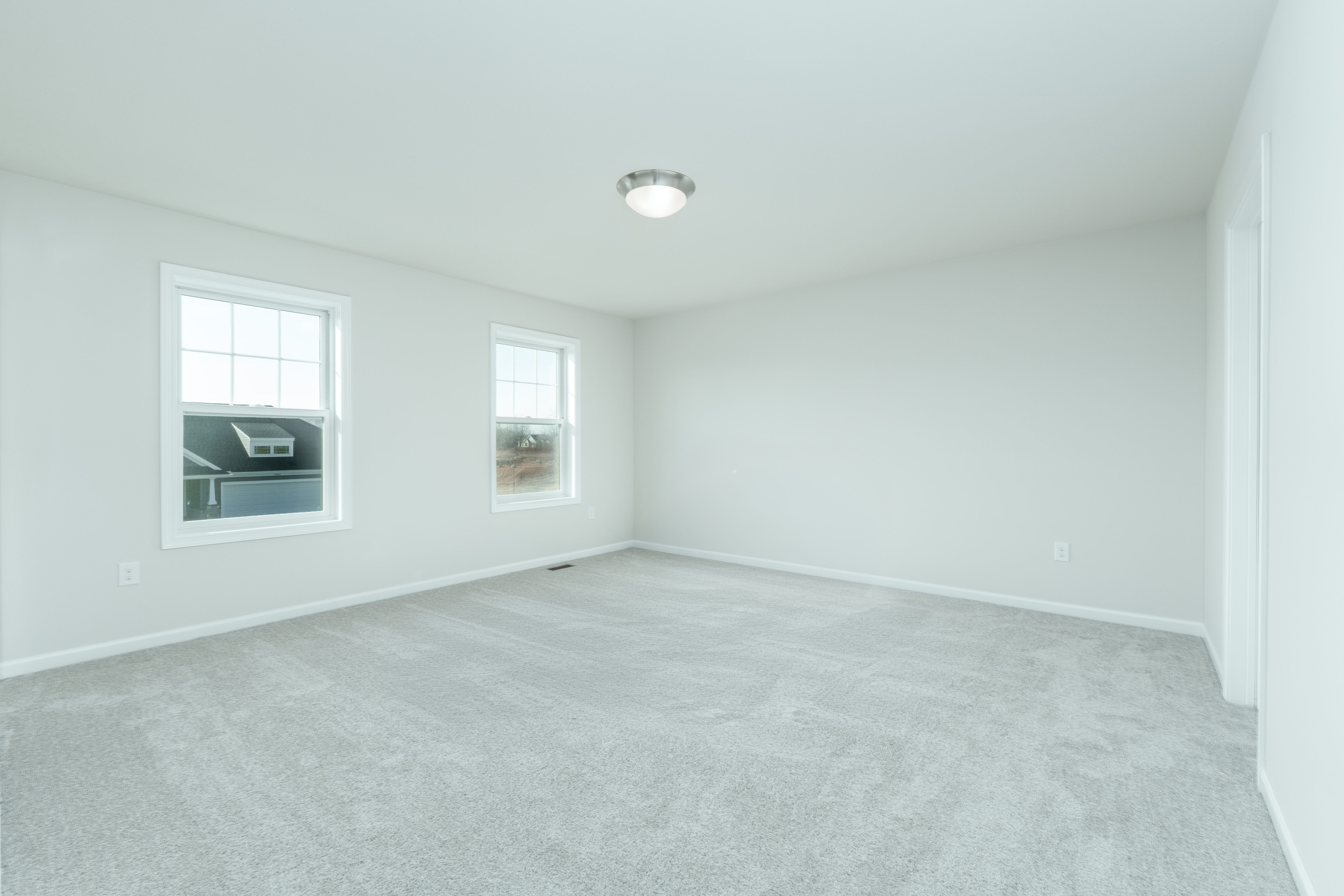 Spacious owners bedroom with soft carpet, double windows, and neutral walls.