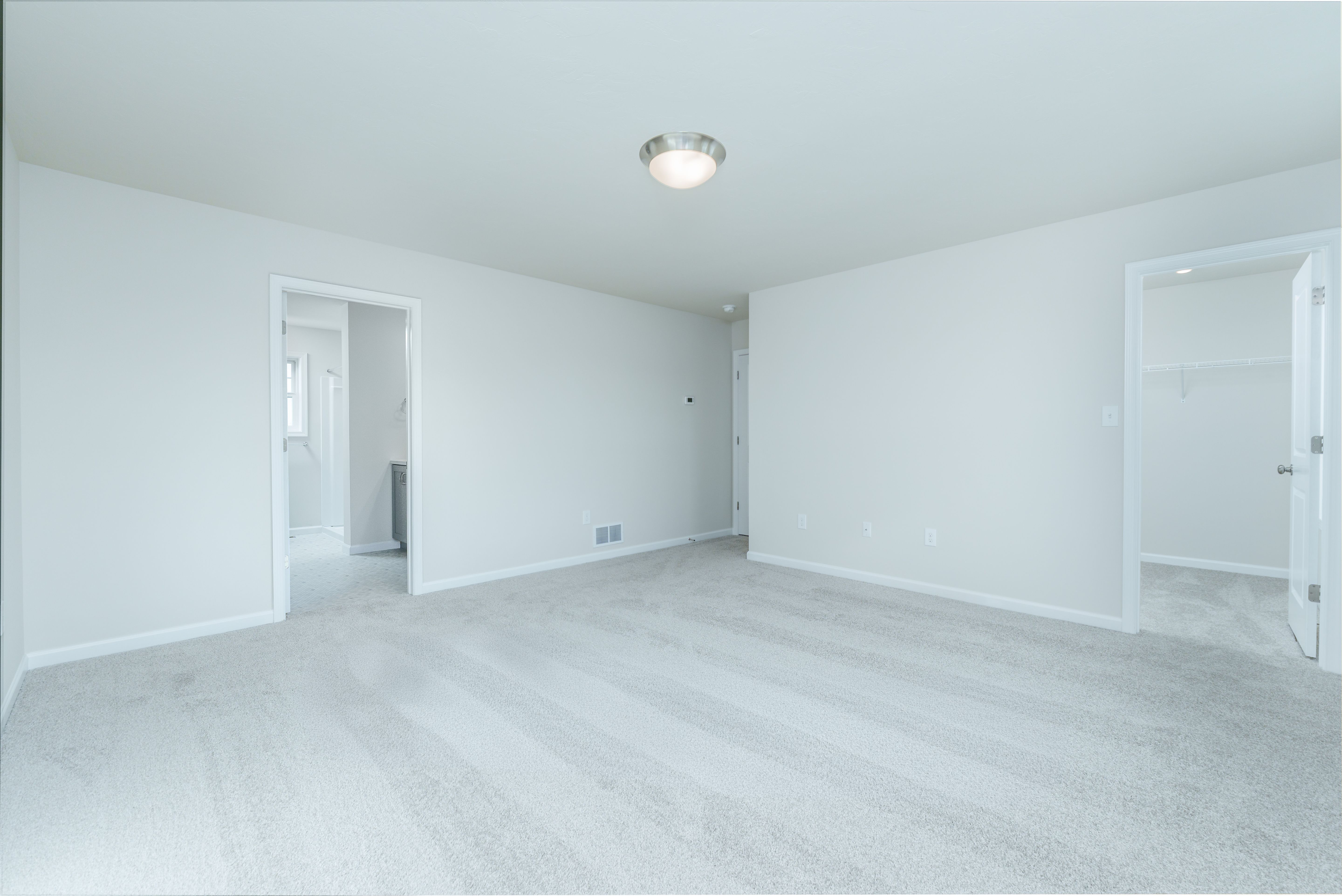 Owners bedroom with plush carpet, single window, and doorway leading to walk-in closet.