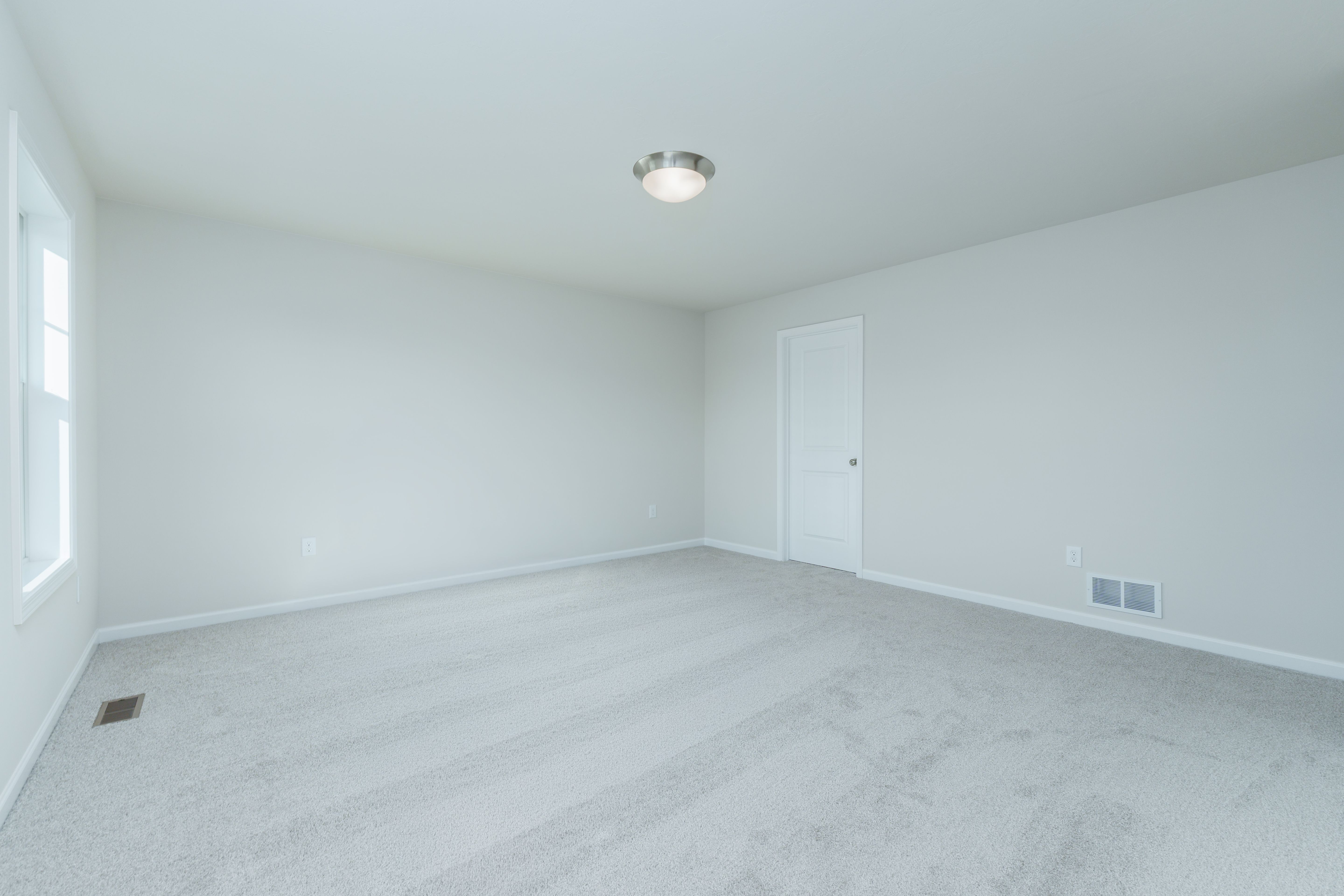 Owners bedroom with plush carpet, two windows, and open doorway to en suite bath.