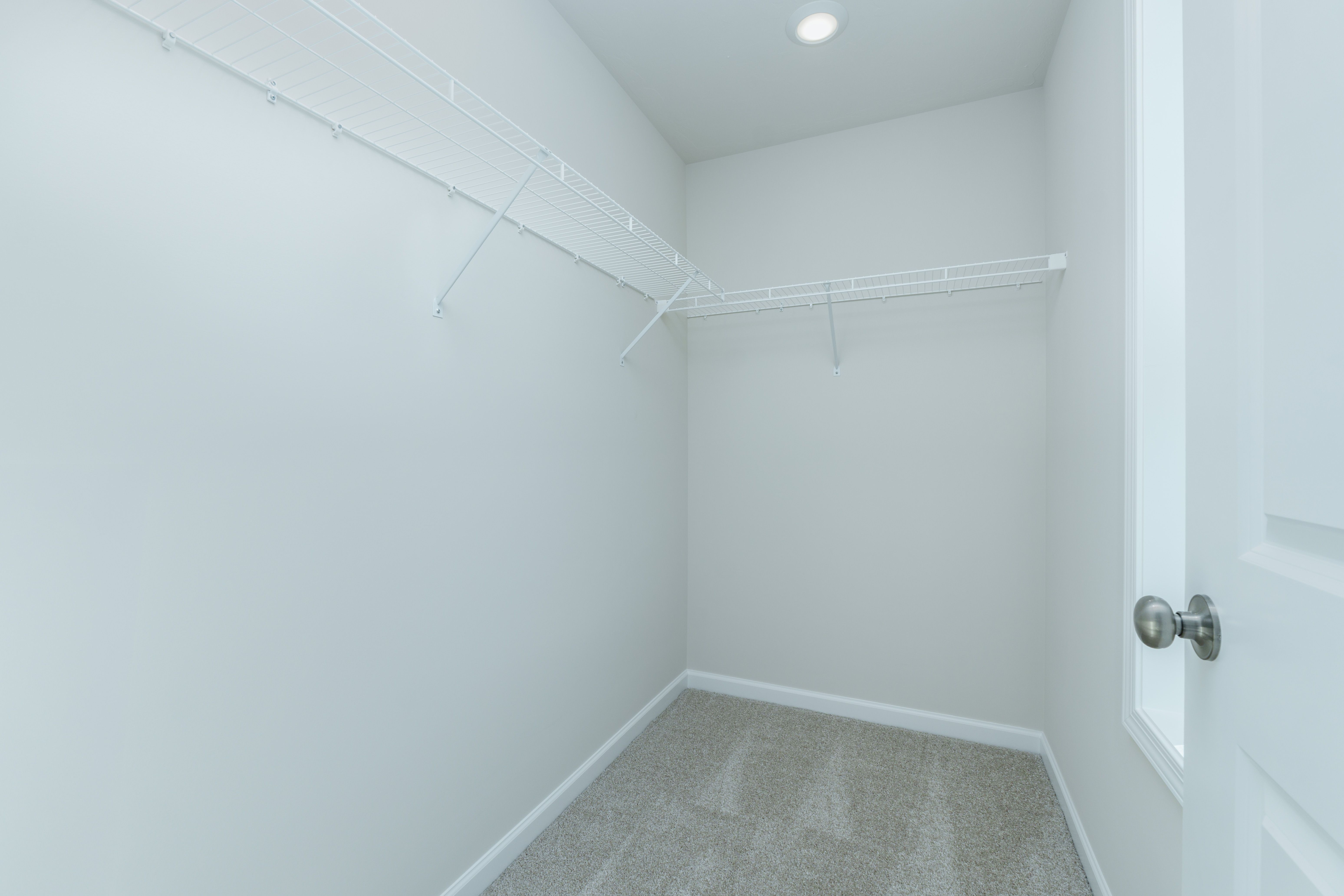Walk-in closet with carpeted floor, white wire shelving, and overhead lighting.