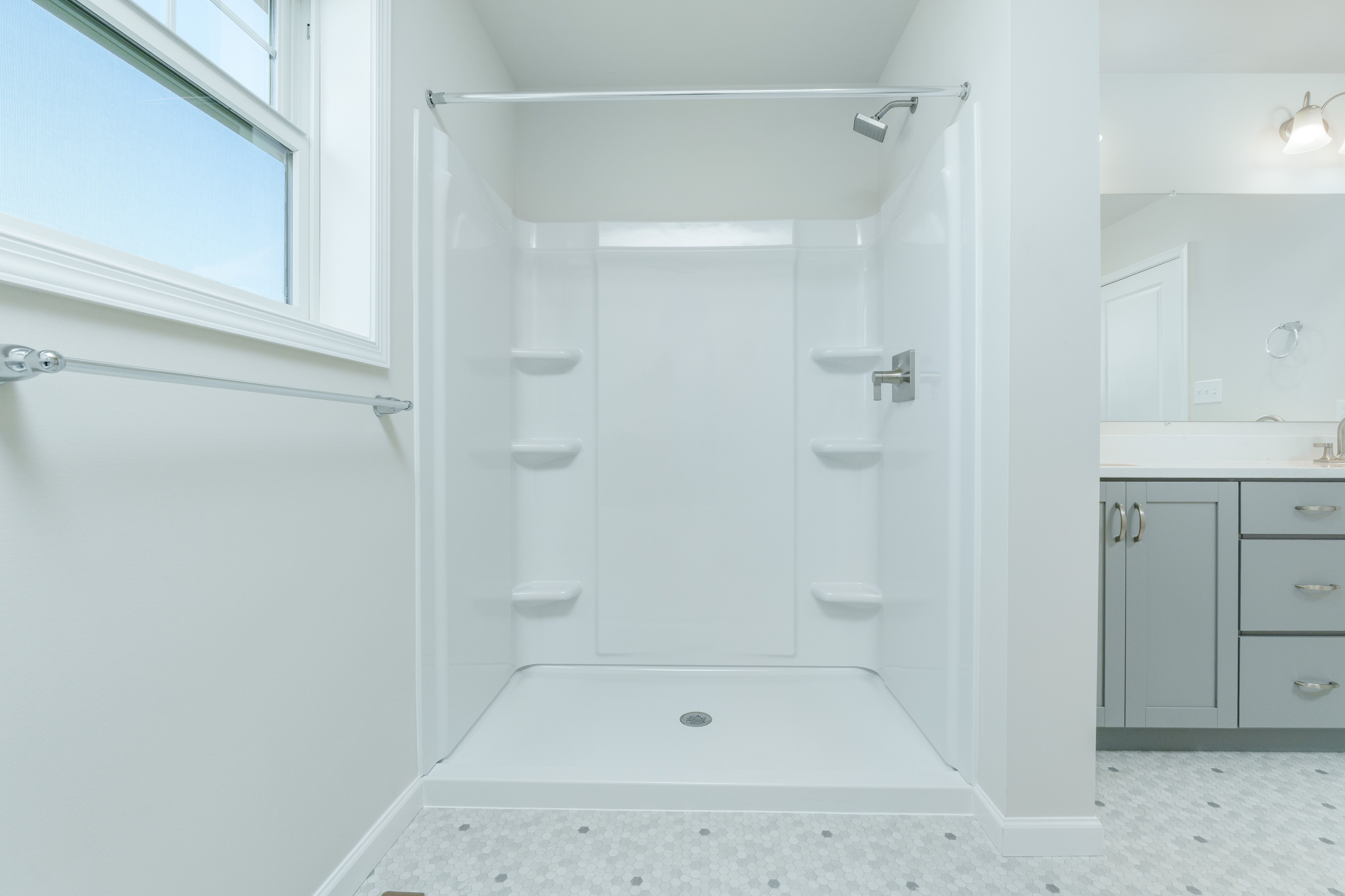 Owners bathroom with walk-in shower, white surround, built-in shelves, and brushed nickel fixtures.