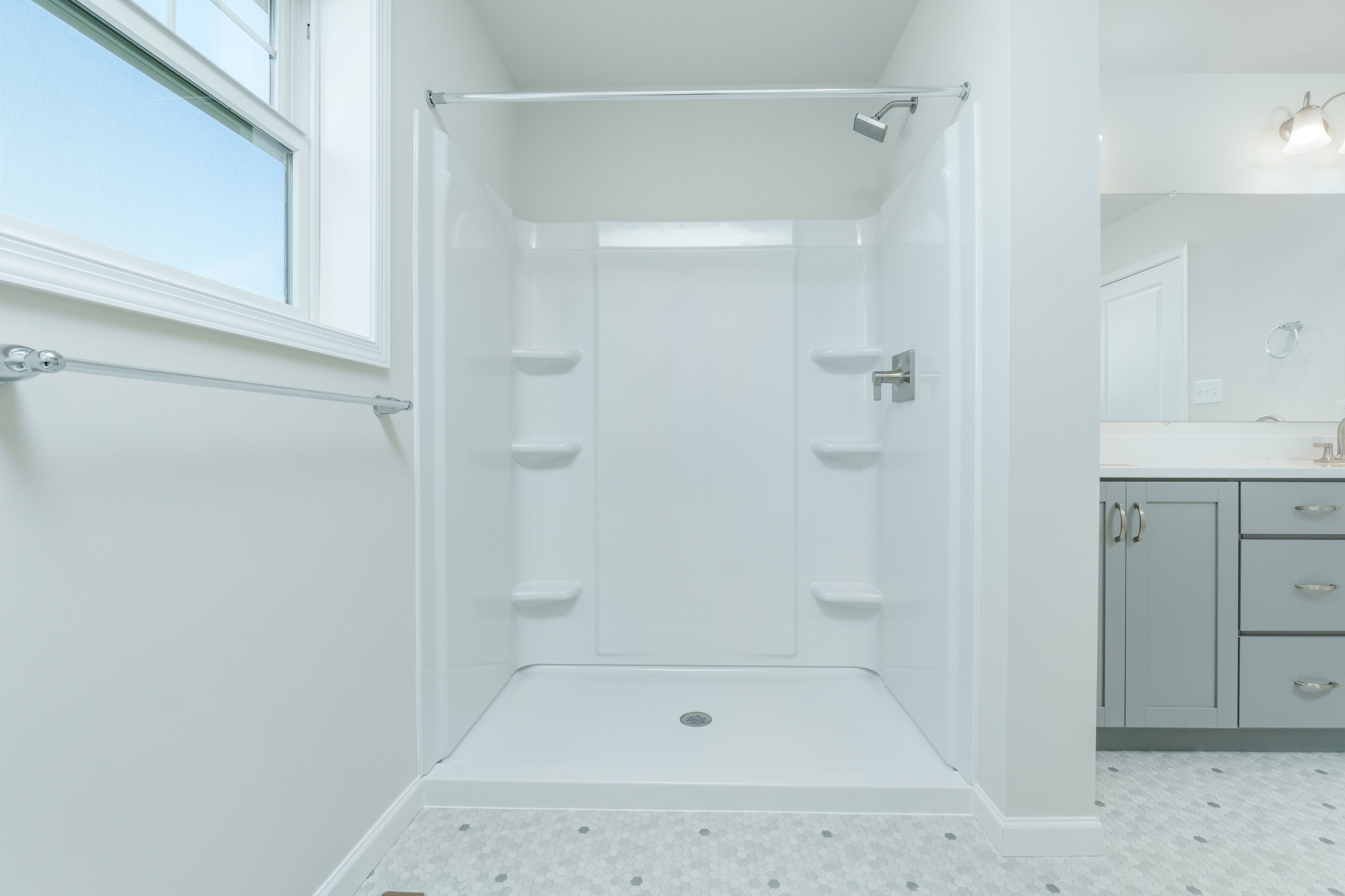 Owners bathroom with walk-in shower, white surround, built-in shelves, and brushed nickel fixtures.