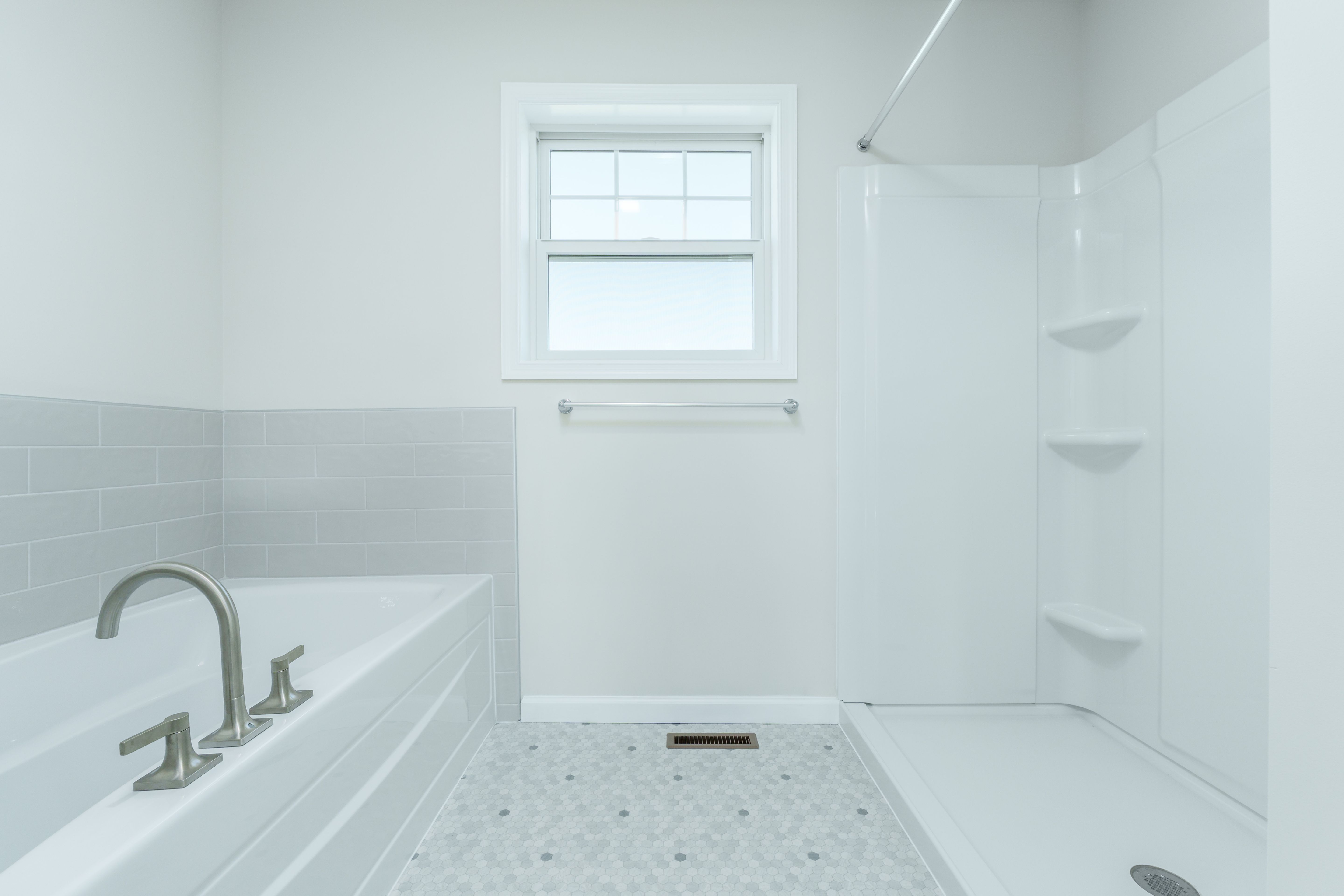 Bright owners bath with soaking tub, separate shower, frosted window, and hex tile flooring.