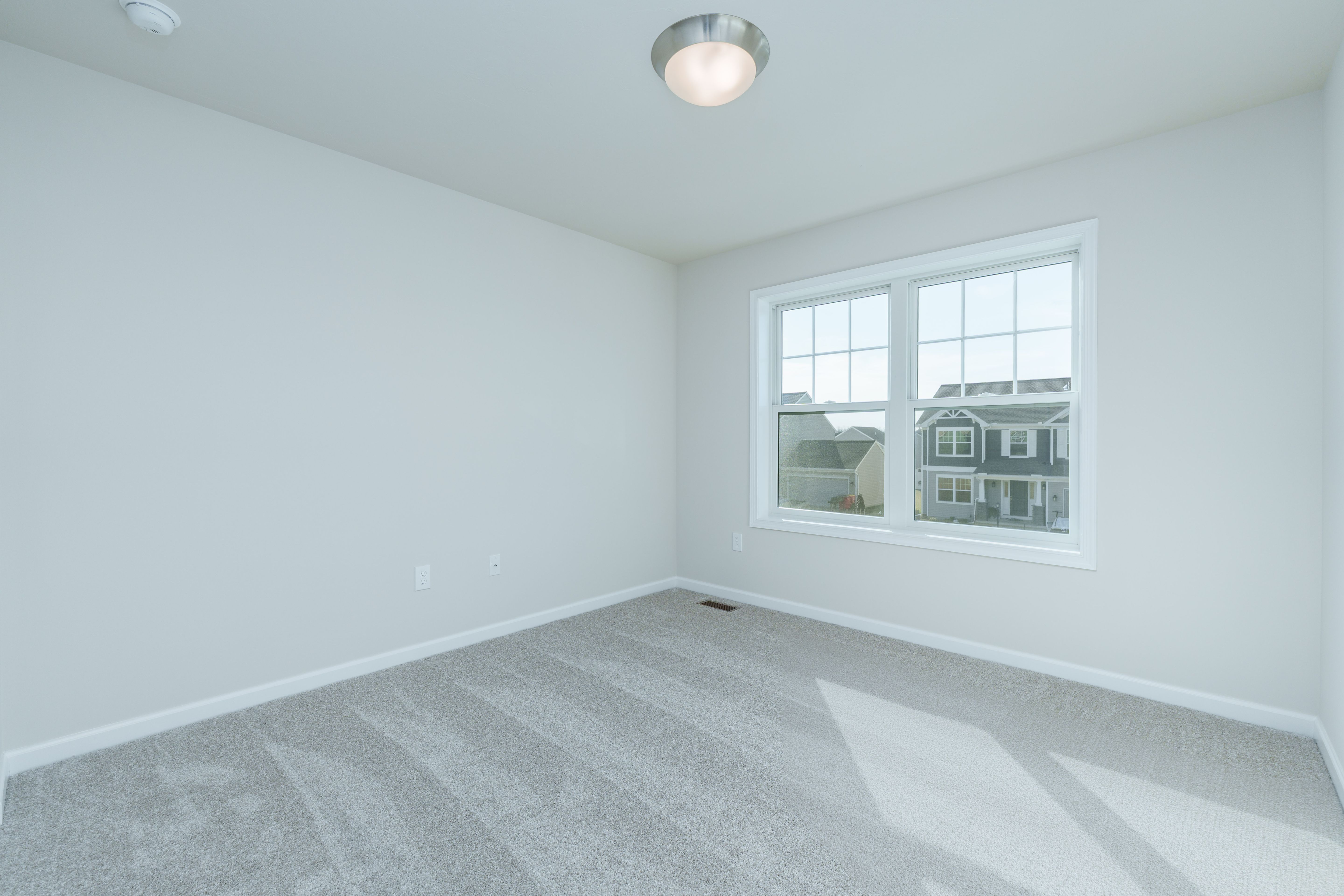 Bedroom with soft carpet, large double window, white walls, and flush mount ceiling light.