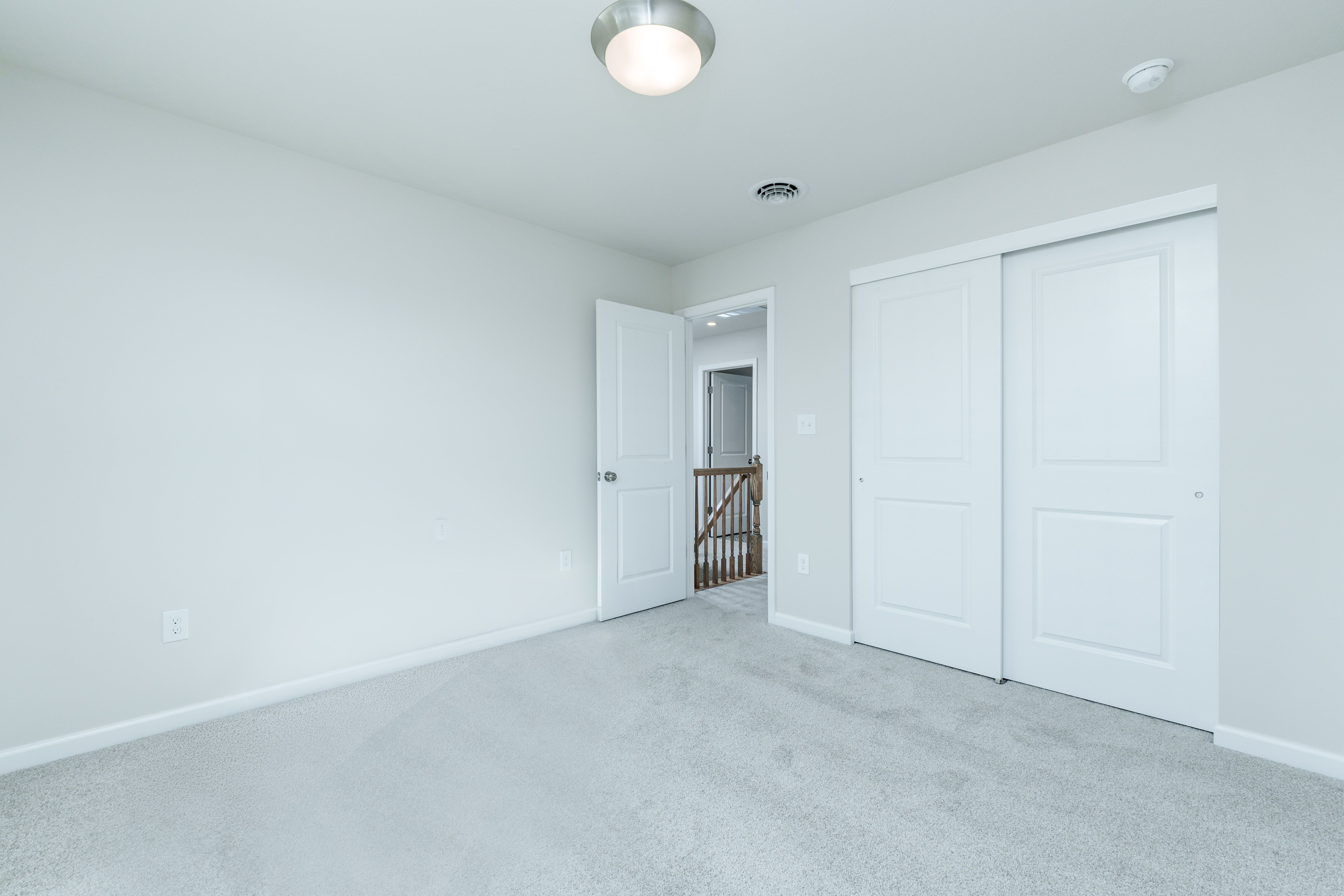 Bedroom with plush carpet, double closet doors, white trim, and open door to hallway.