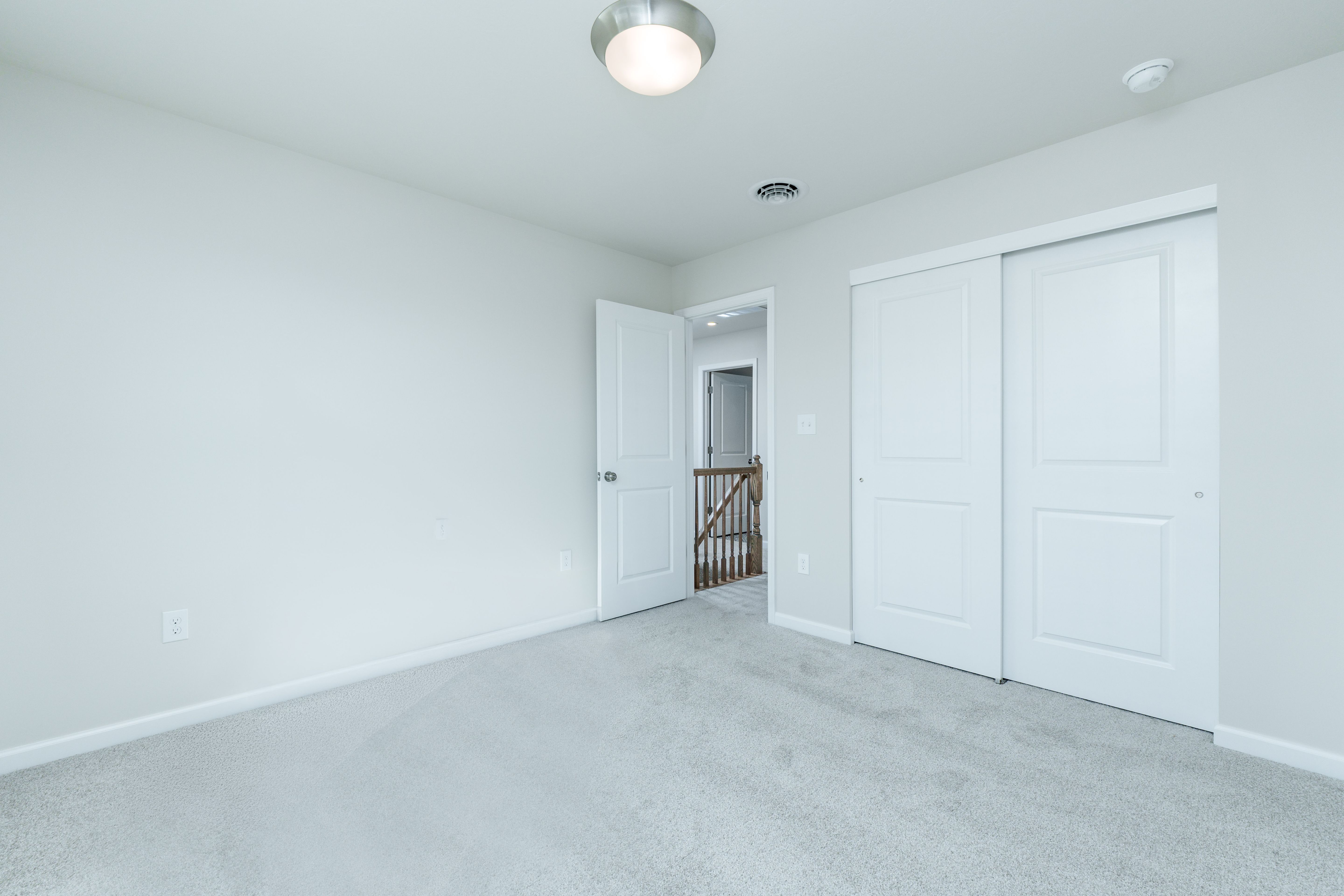 Bedroom with plush carpet, double closet doors, white trim, and open door to hallway.