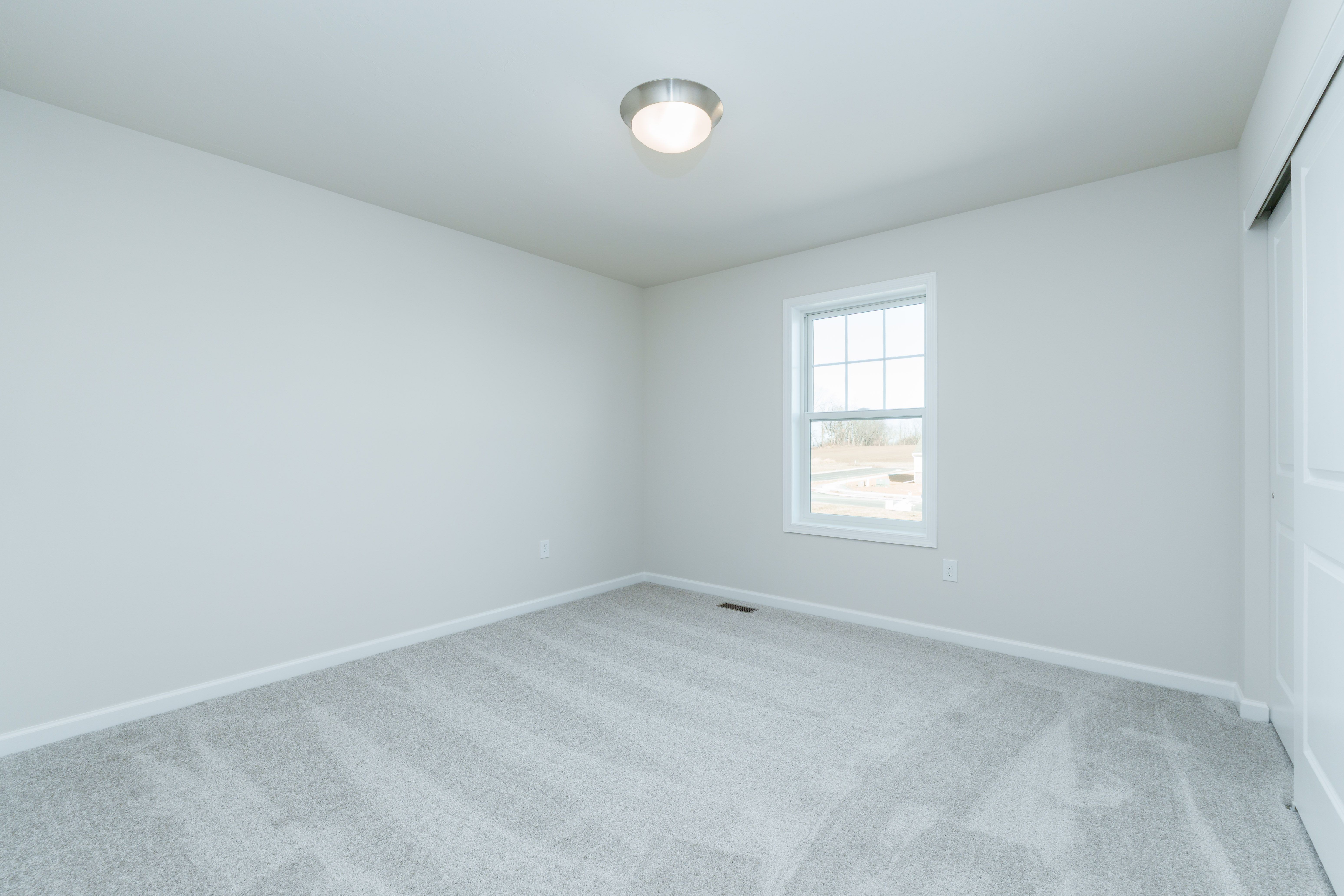 Bedroom with soft carpet, single window, white walls, and flush mount ceiling light.