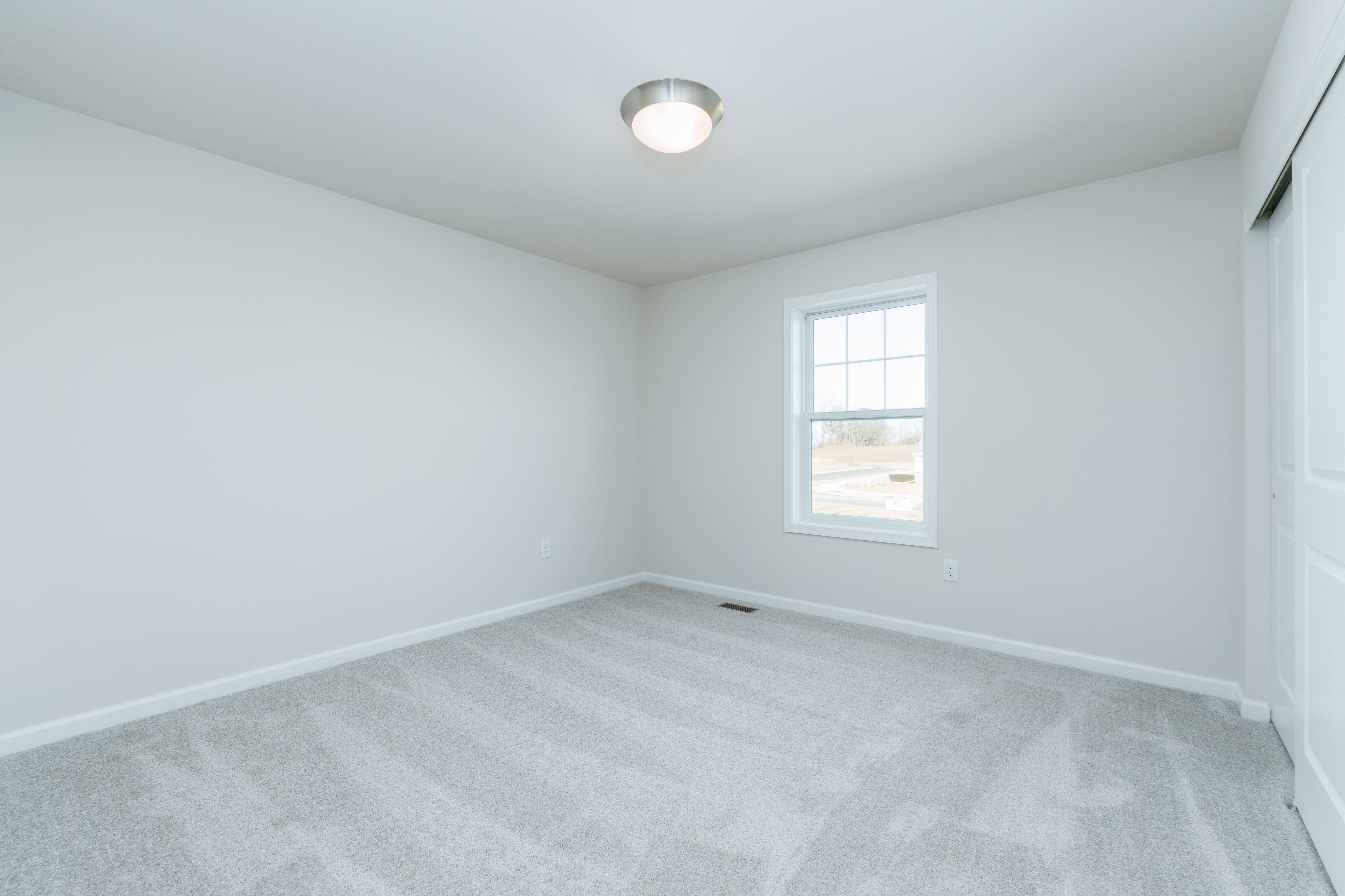 Bedroom with soft carpet, single window, white walls, and flush mount ceiling light.
