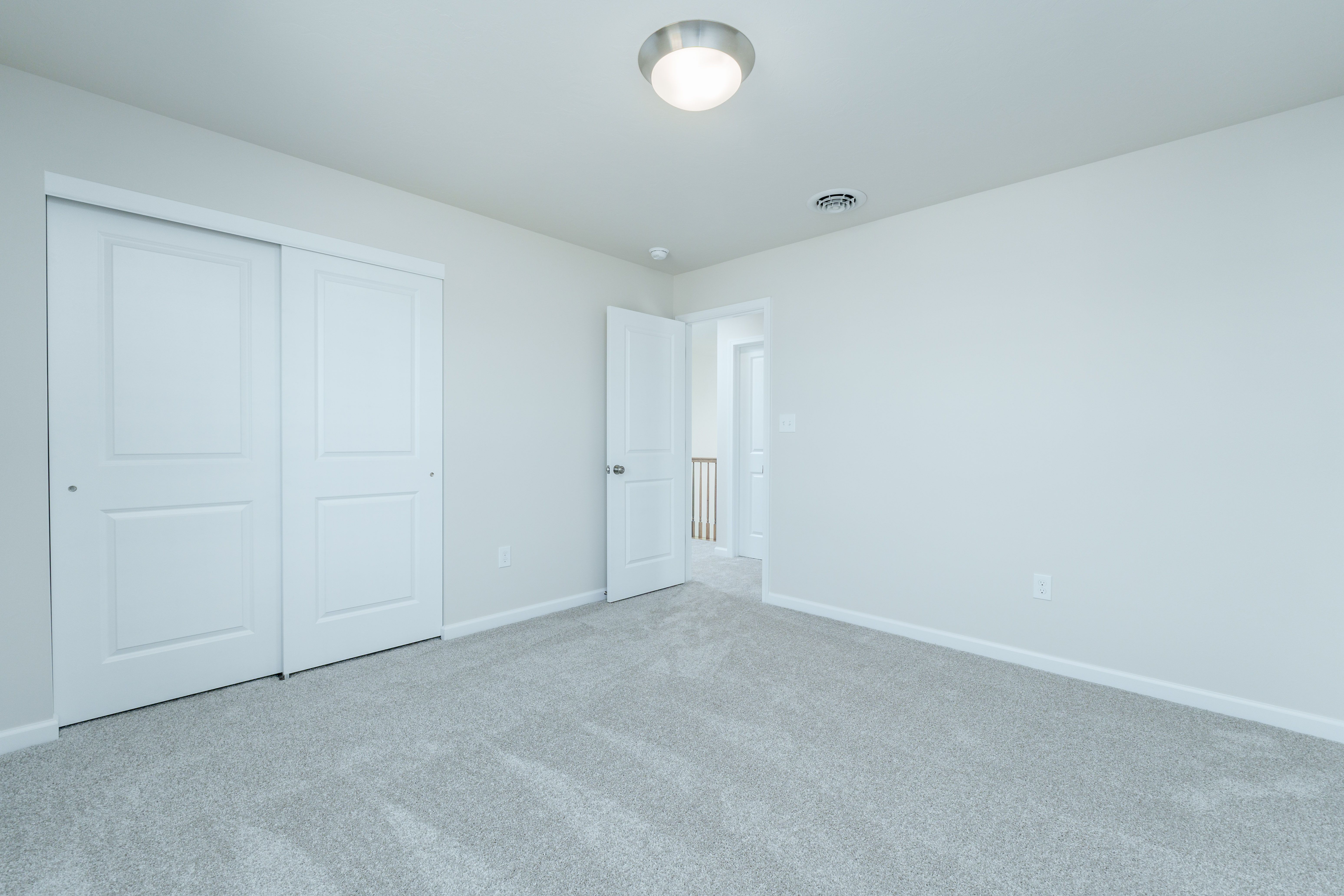Bedroom with plush carpet, sliding closet doors, and open door to hallway.