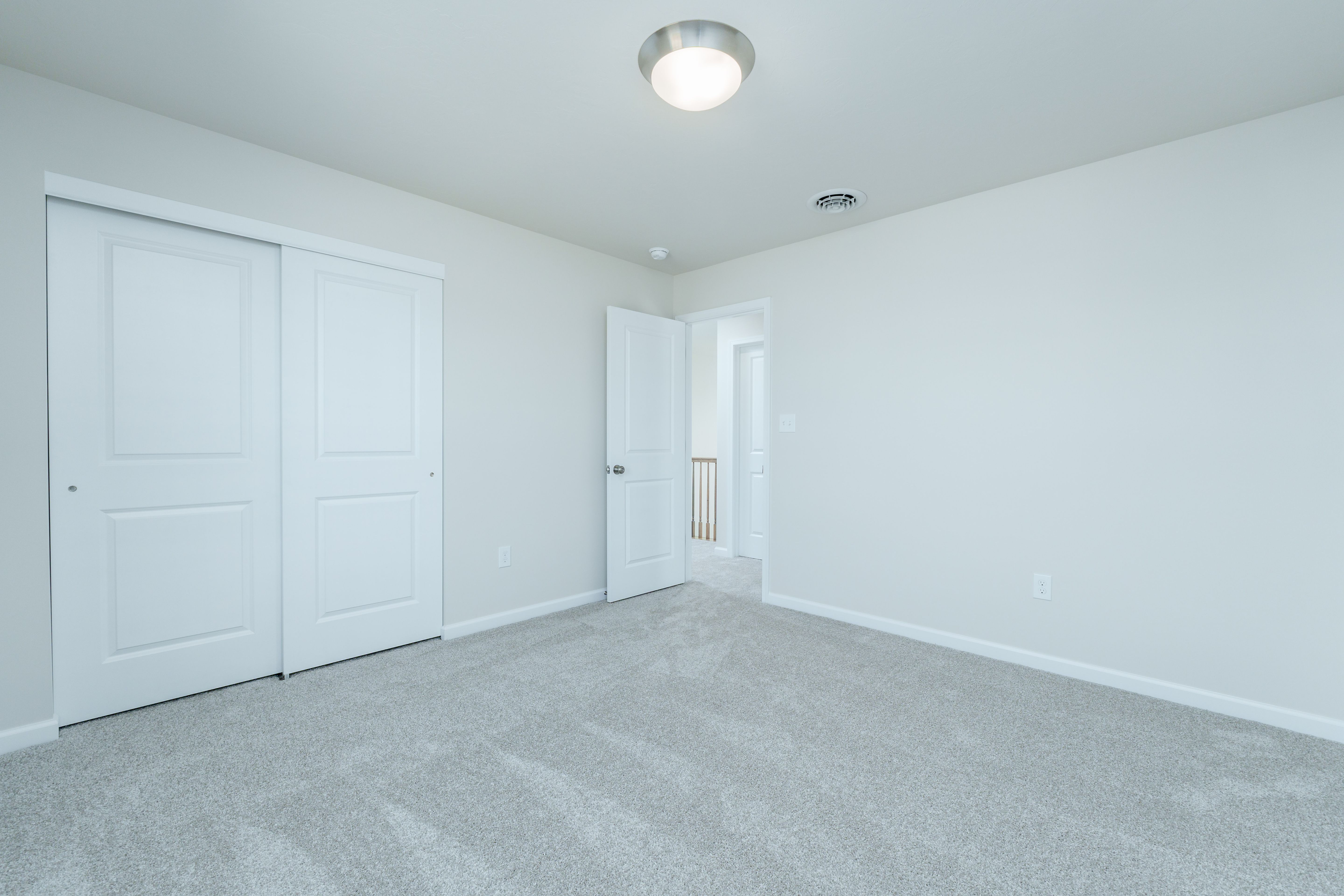 Bedroom with plush carpet, sliding closet doors, and open door to hallway.