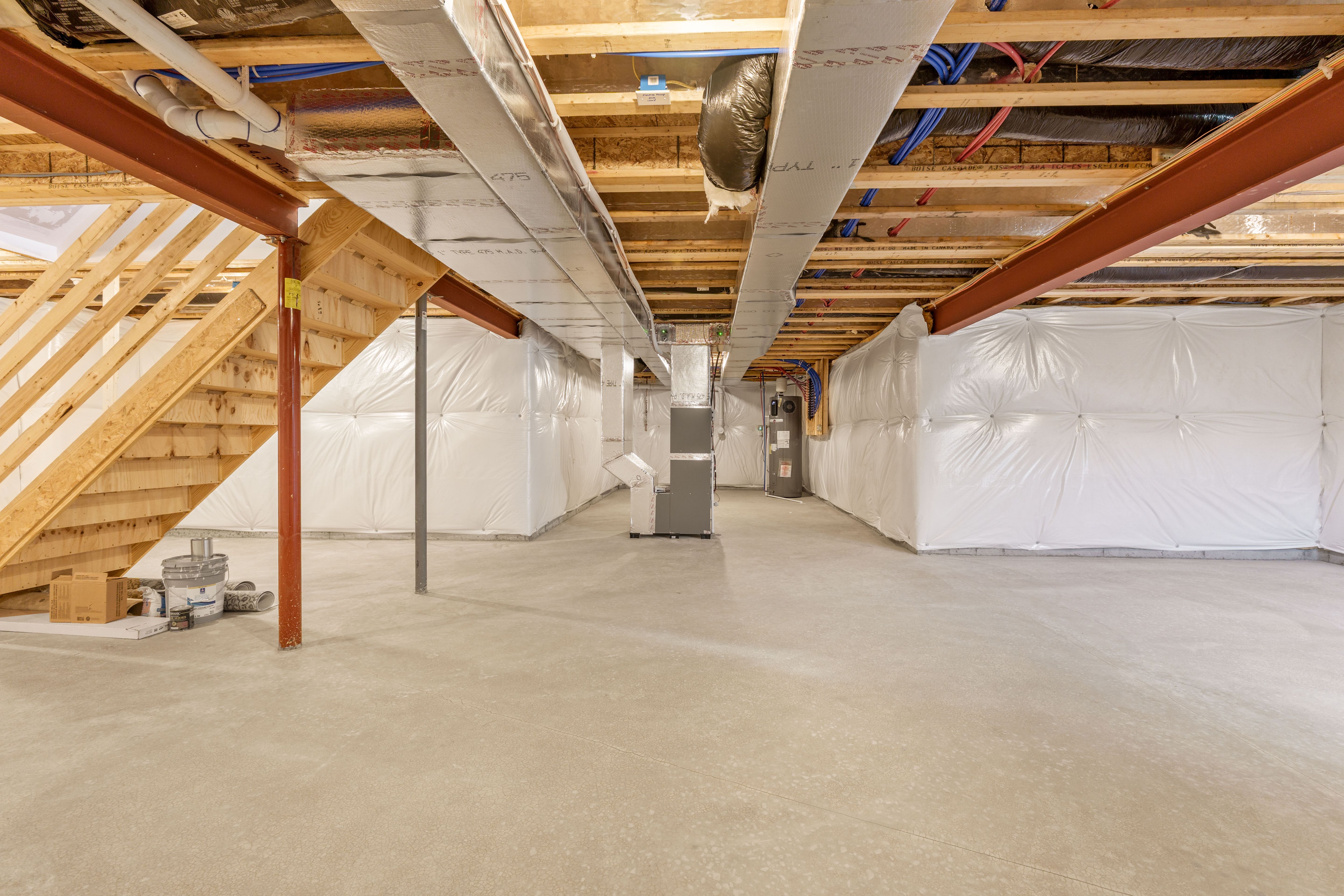 Spacious unfinished basement with exposed ductwork, furnace, concrete floors, and insulated walls.
