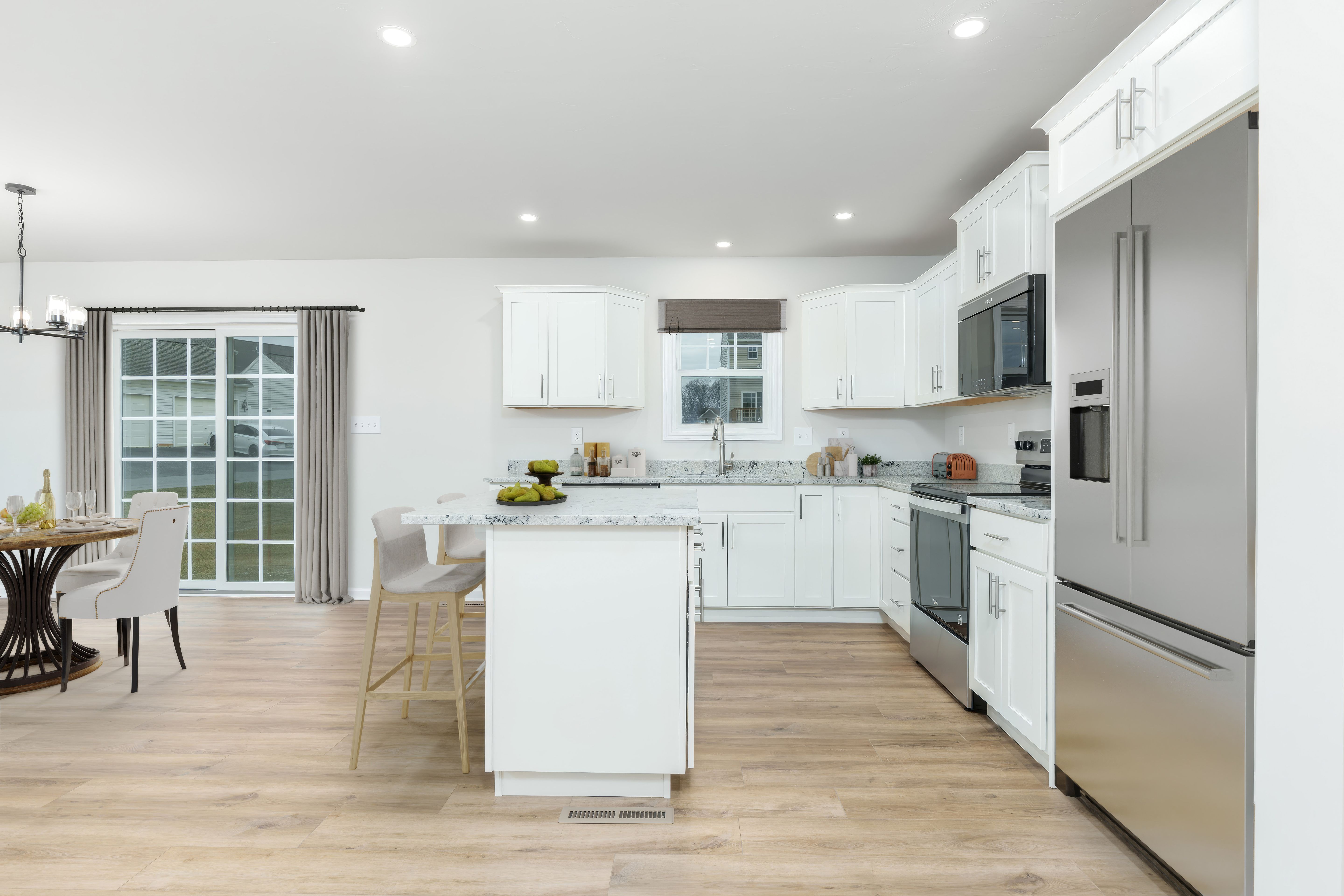 Open kitchen with white cabinets, granite countertops, stainless appliances, center island, and luxury vinyl plank flooring.