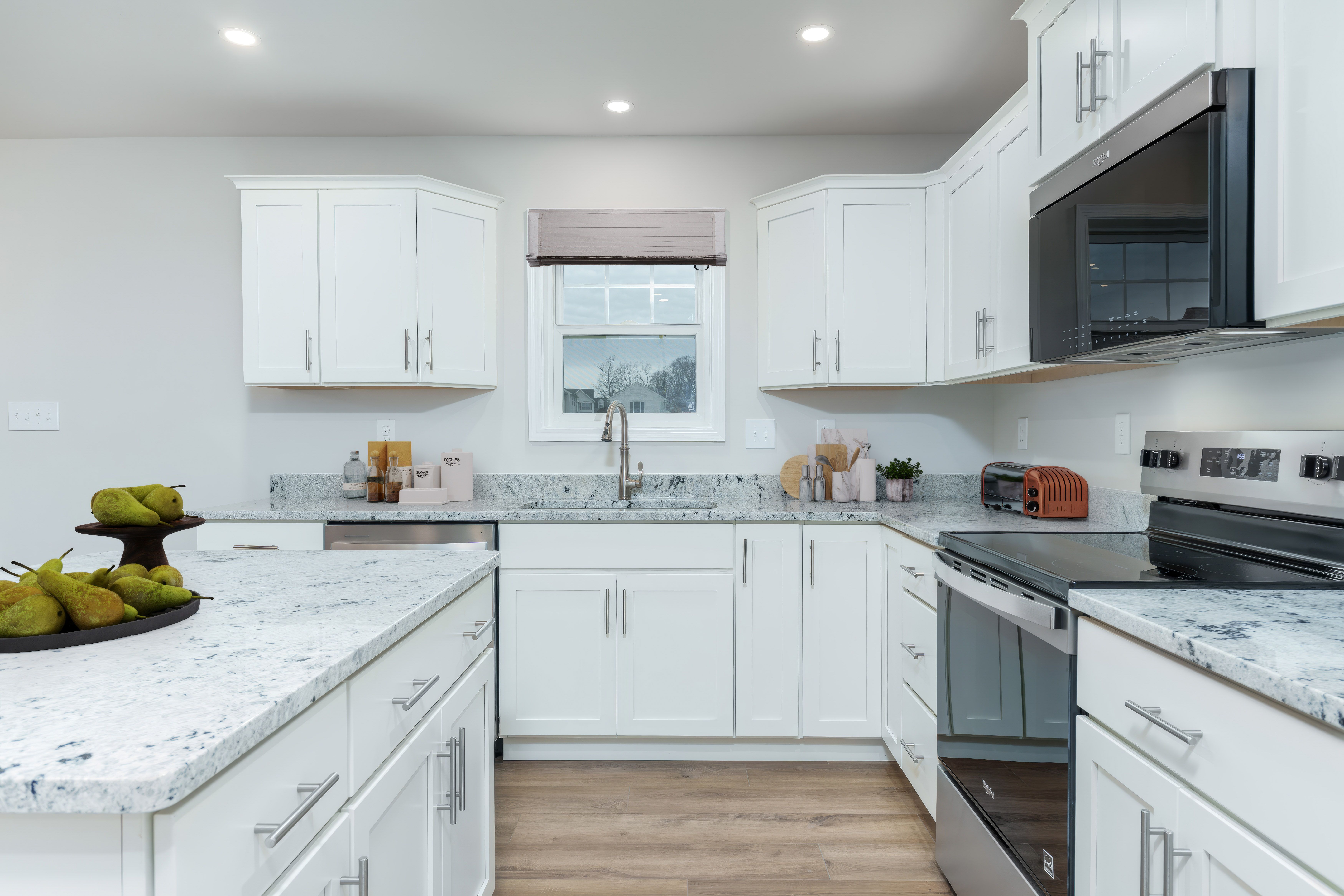 Bright kitchen with white cabinetry, granite countertops, stainless appliances, and window above the sink.