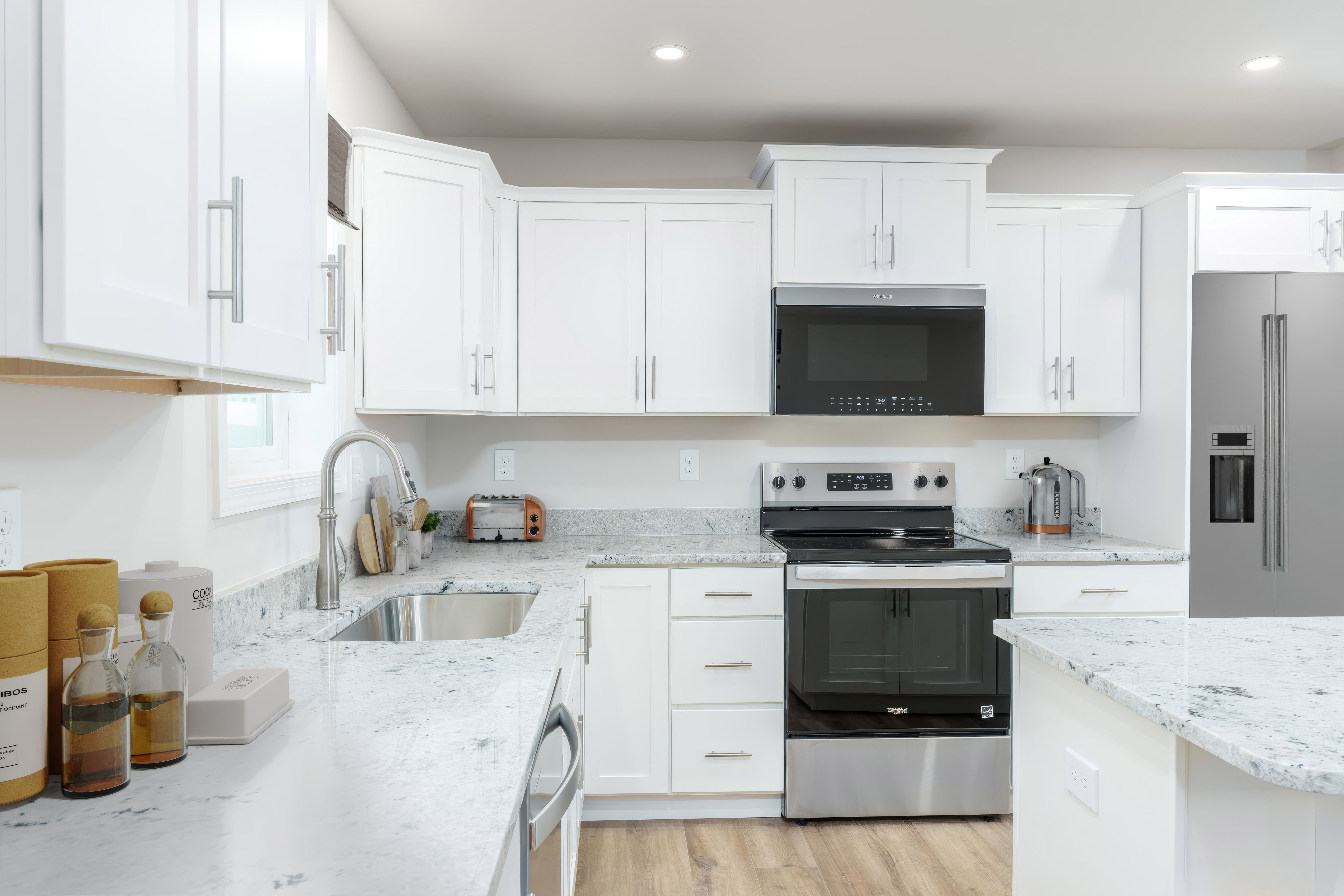 Kitchen with granite countertops, stainless range and microwave, white cabinets, and large island workspace.