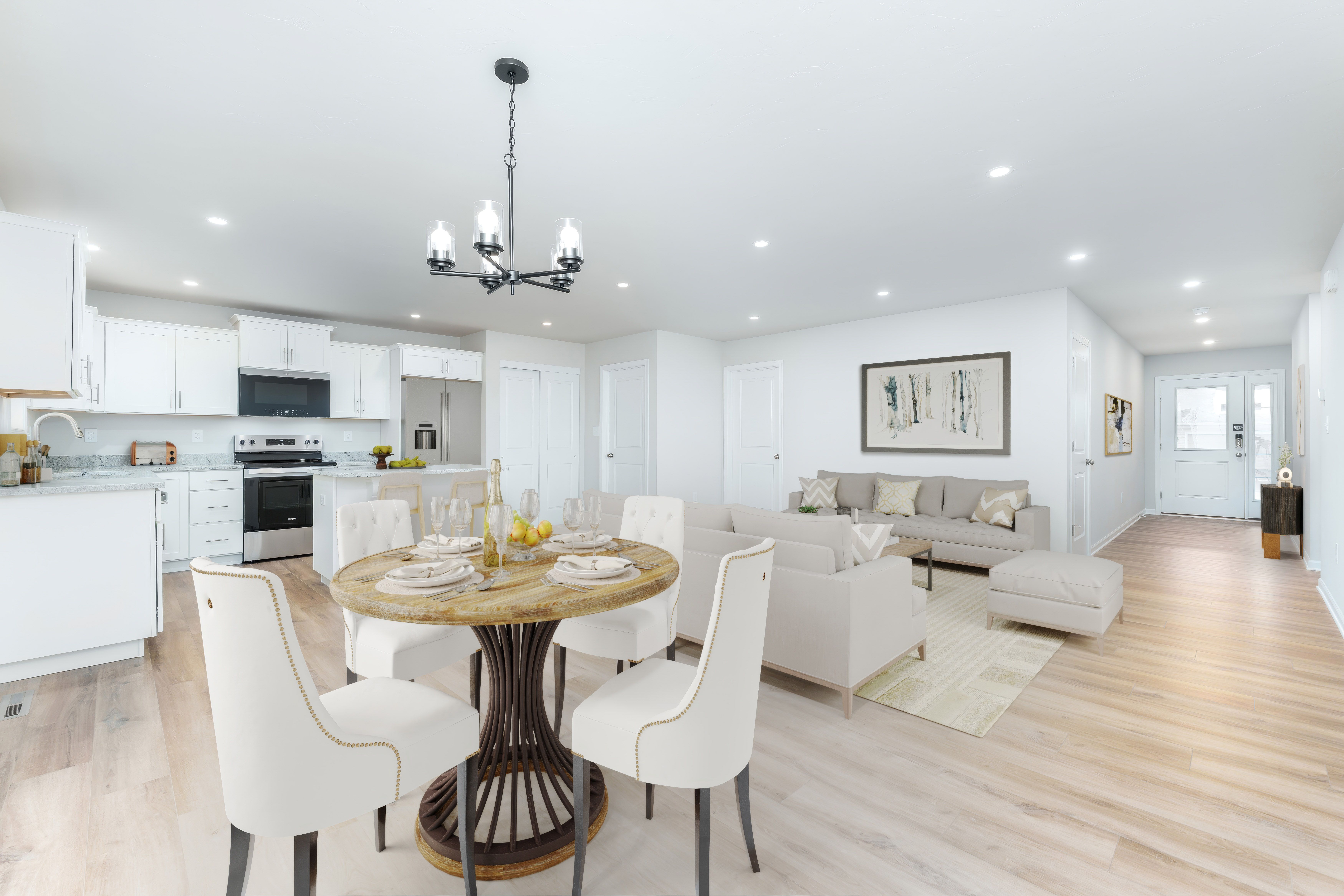 Open dining and living space beside kitchen with round dining table, sofa seating, and luxury vinyl plank flooring.