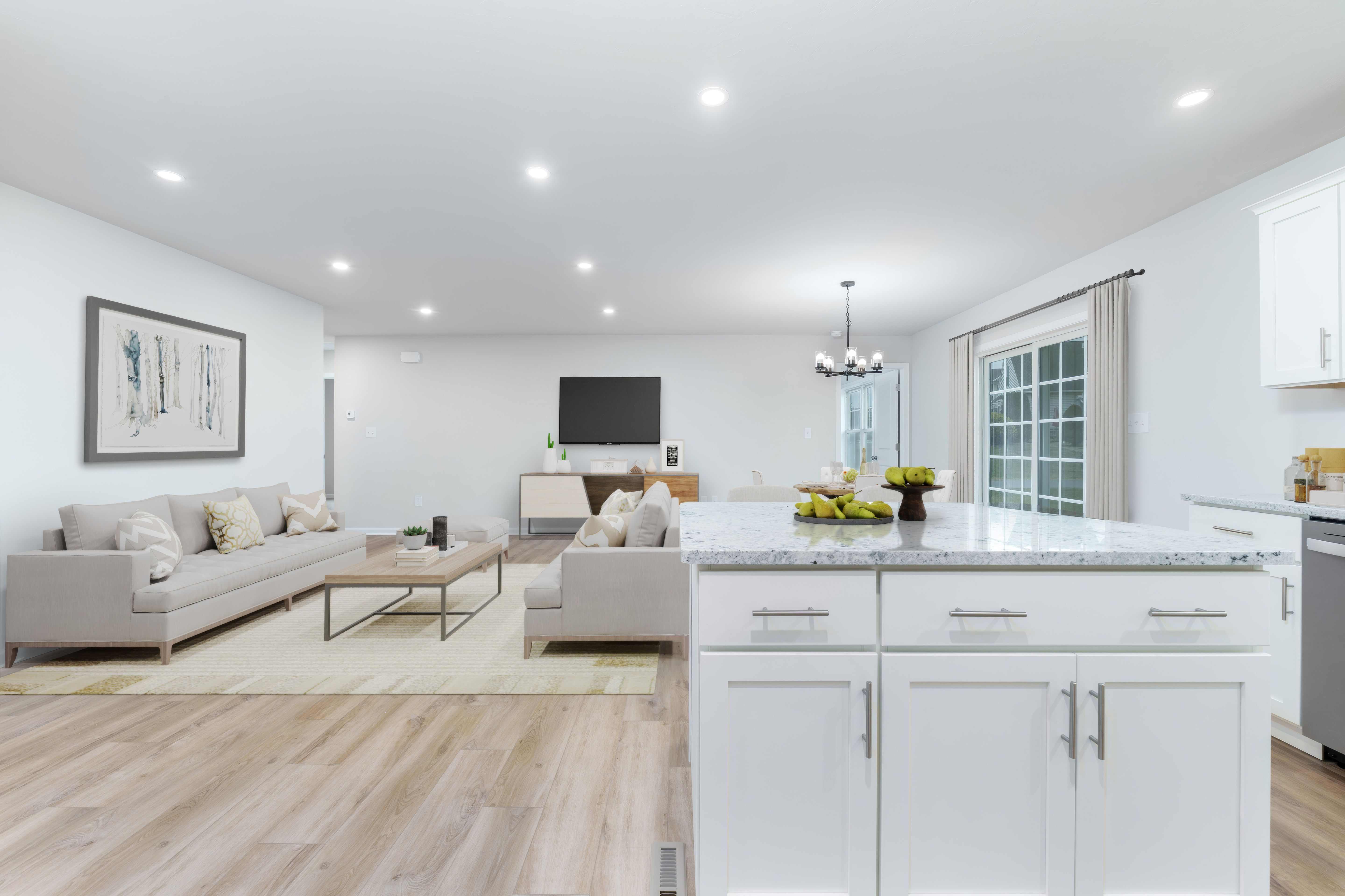 View from kitchen island toward living room with sofas, coffee table, dining area, and sliding glass door.