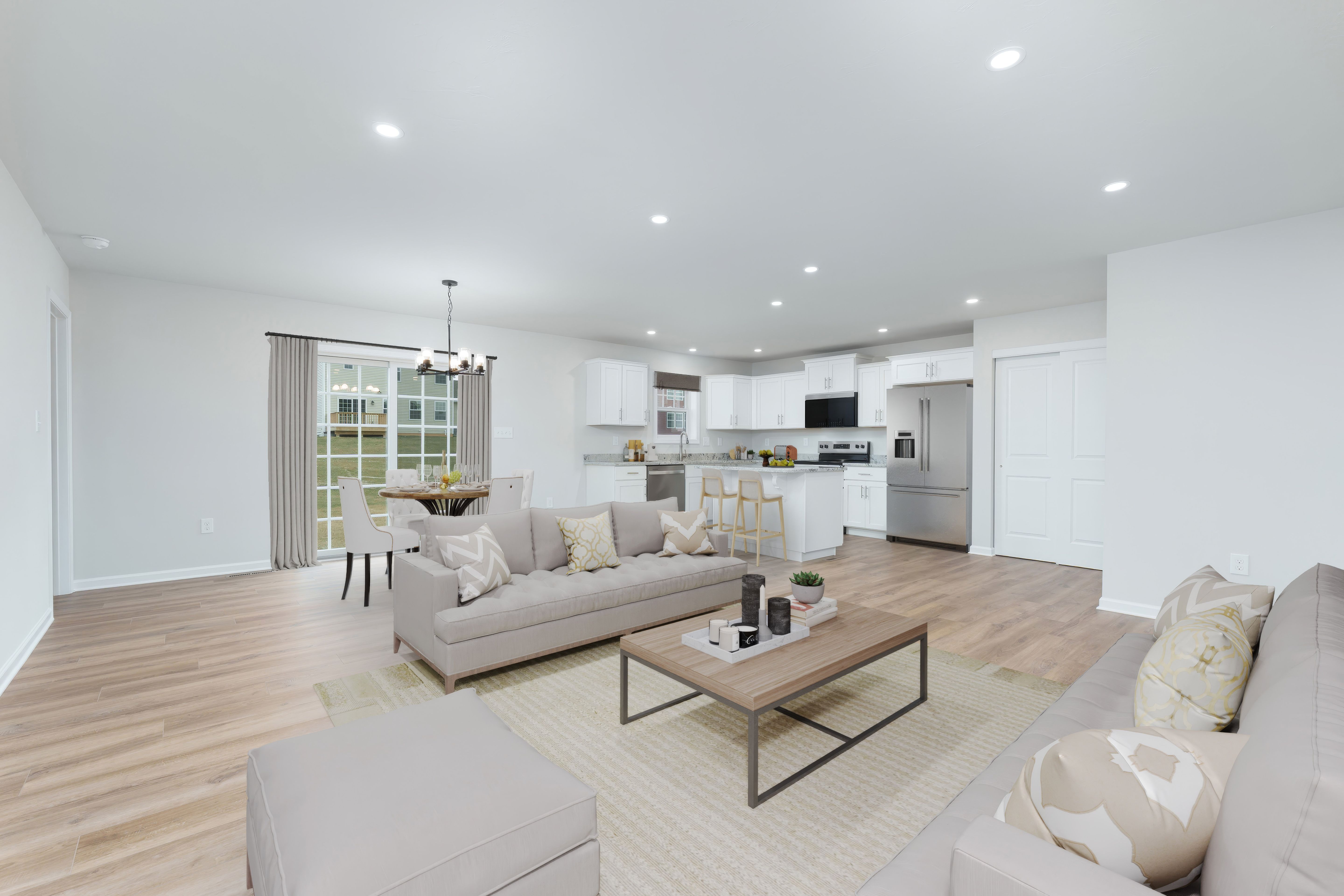 Open concept living area with kitchen, dining table, sofas, and luxury vinyl plank flooring throughout.