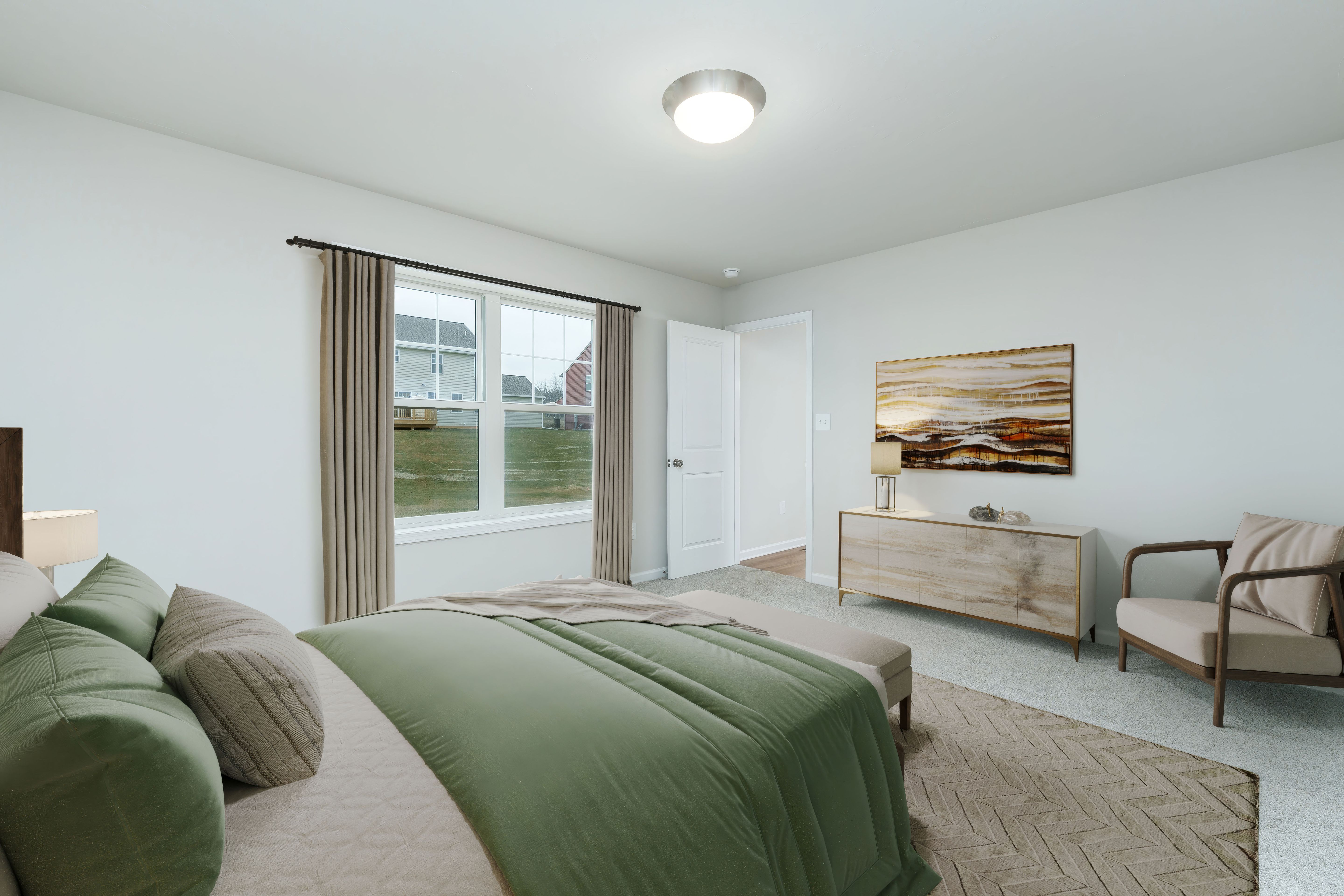 Spacious owners bedroom with large window, dresser with artwork above, and soft carpet flooring.