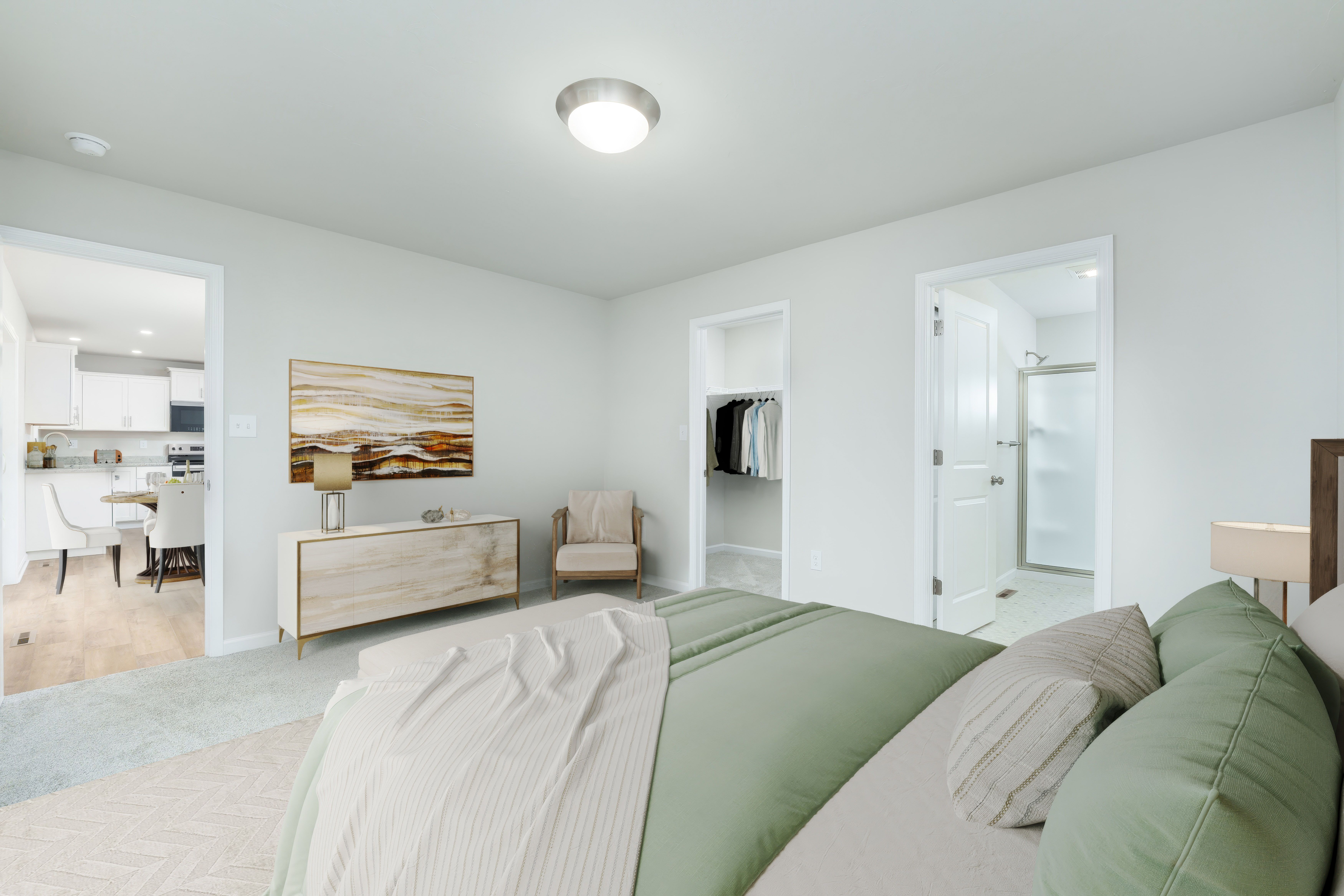 Owners bedroom with bed in foreground, doorway to walk-in closet and bathroom, and soft carpet flooring.