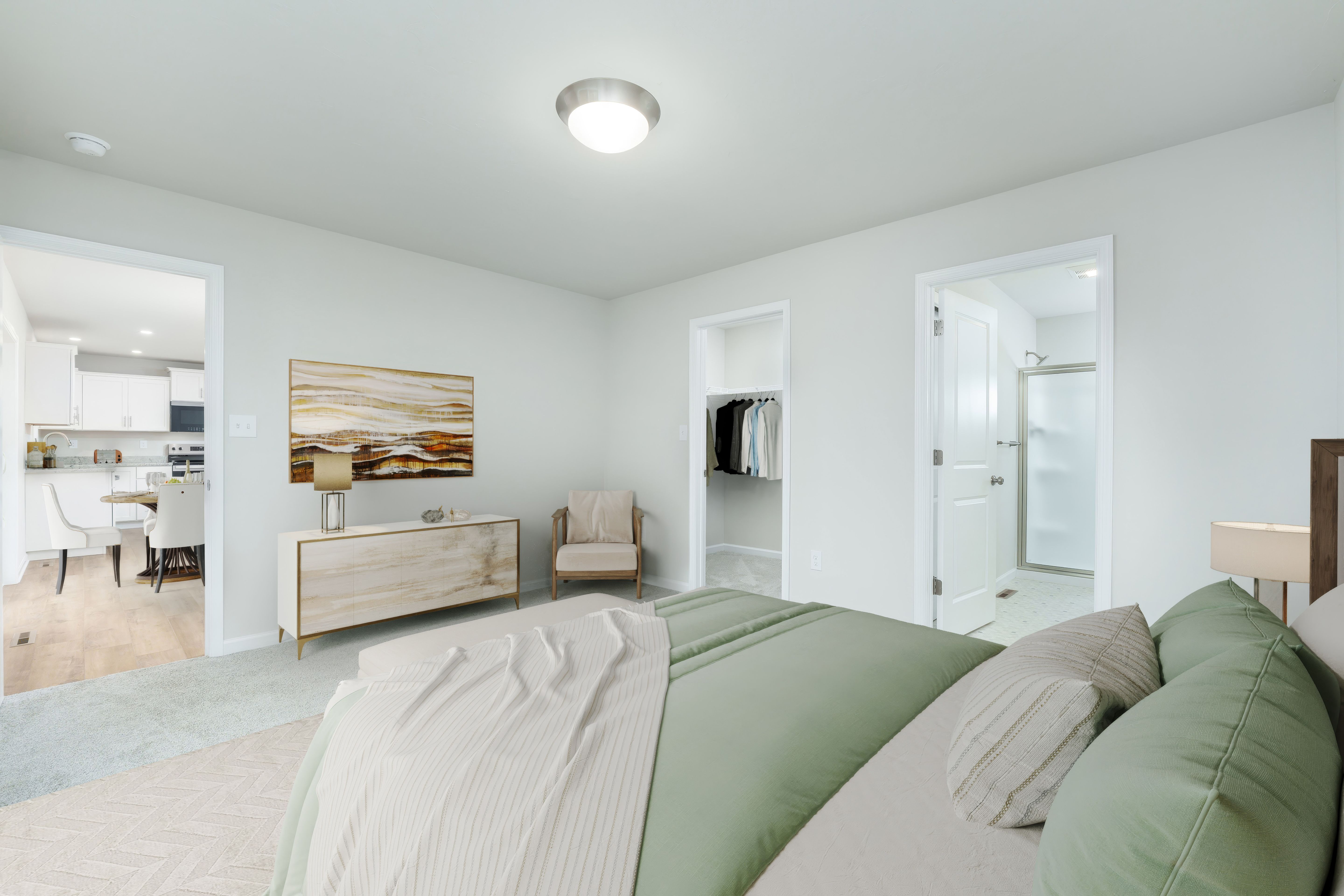 Owners bedroom with bed in foreground, doorway to walk-in closet and bathroom, and soft carpet flooring.