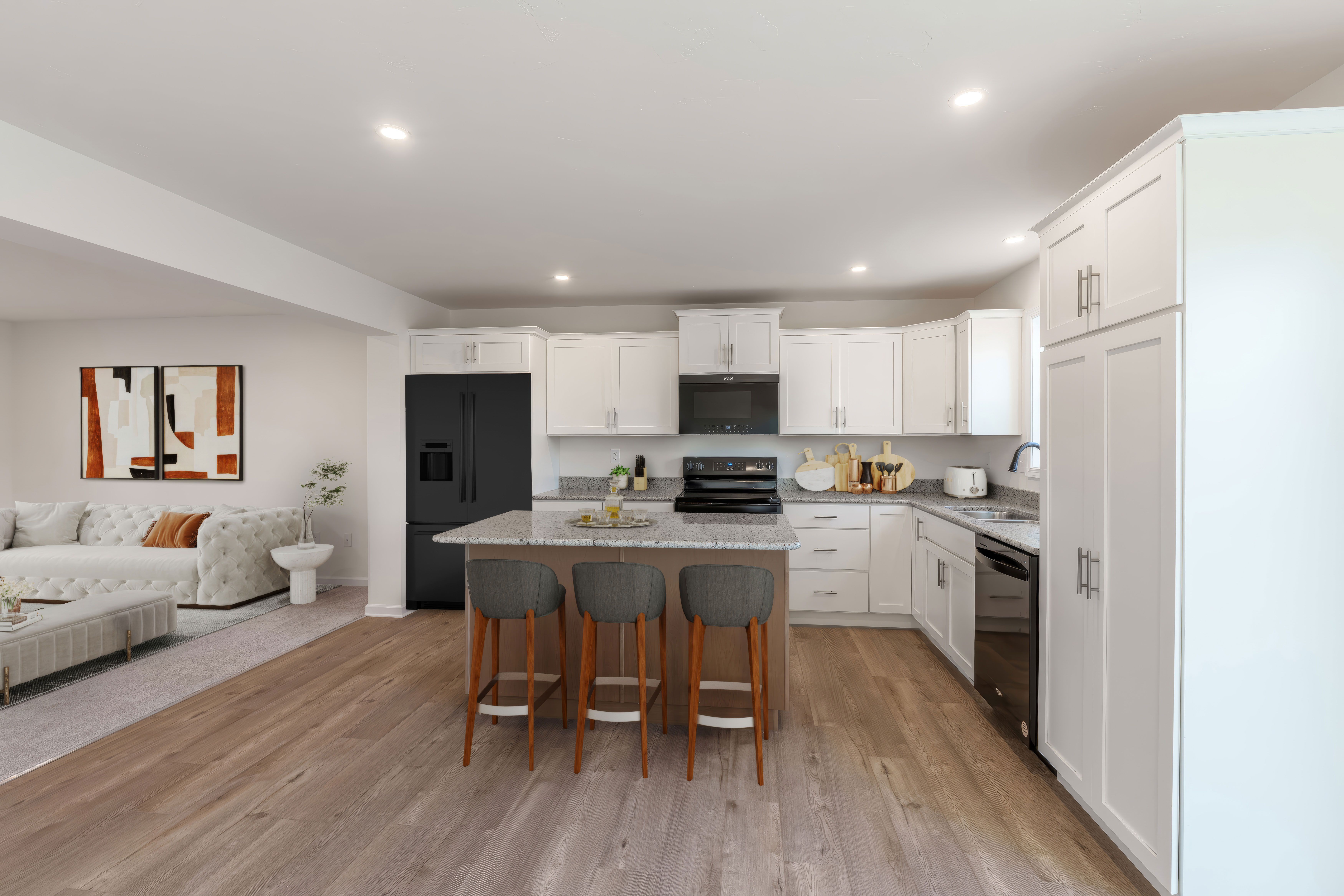 Open kitchen with island seating flowing into living area with sofa and modern decor