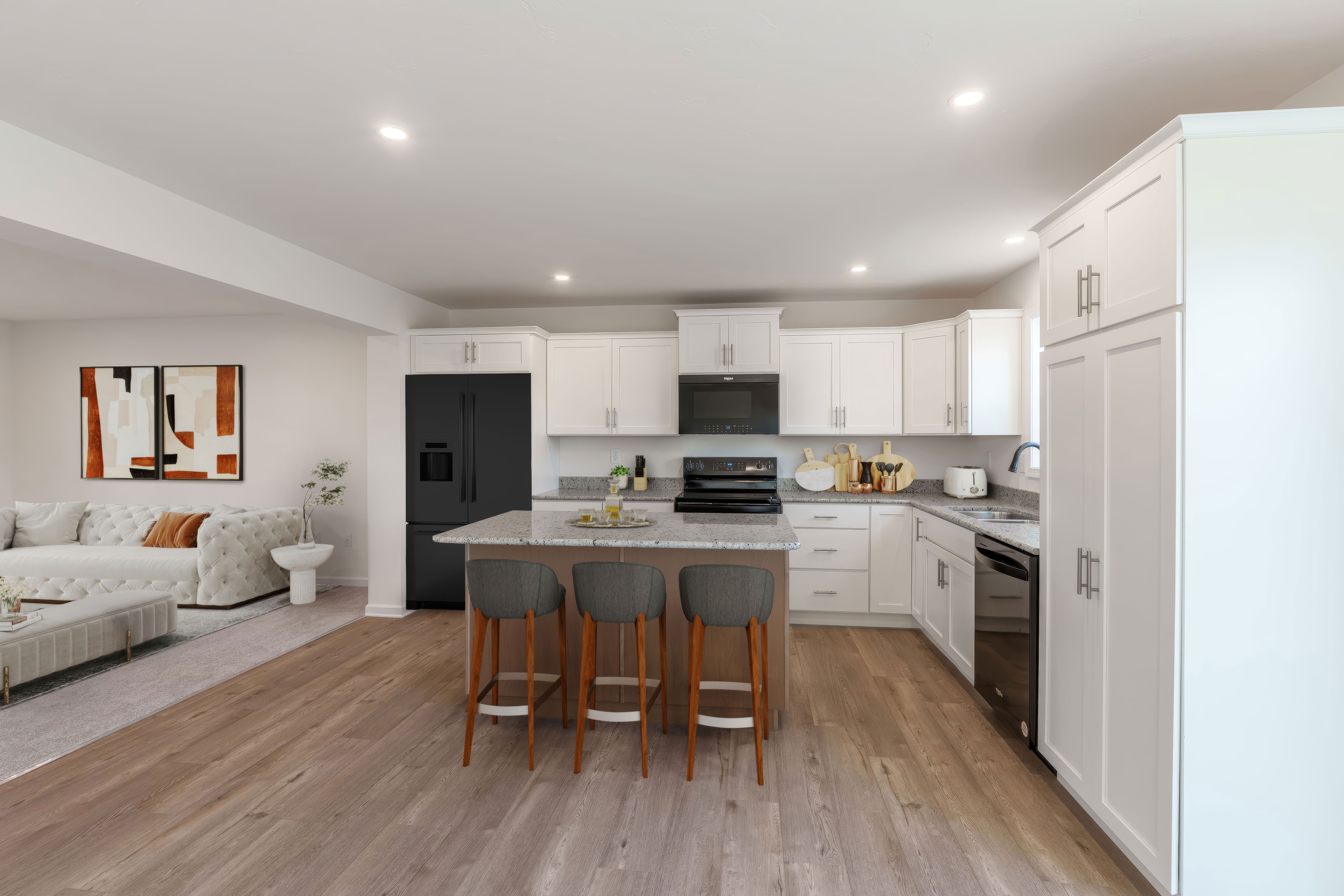 Open kitchen with island seating flowing into living area with sofa and modern decor