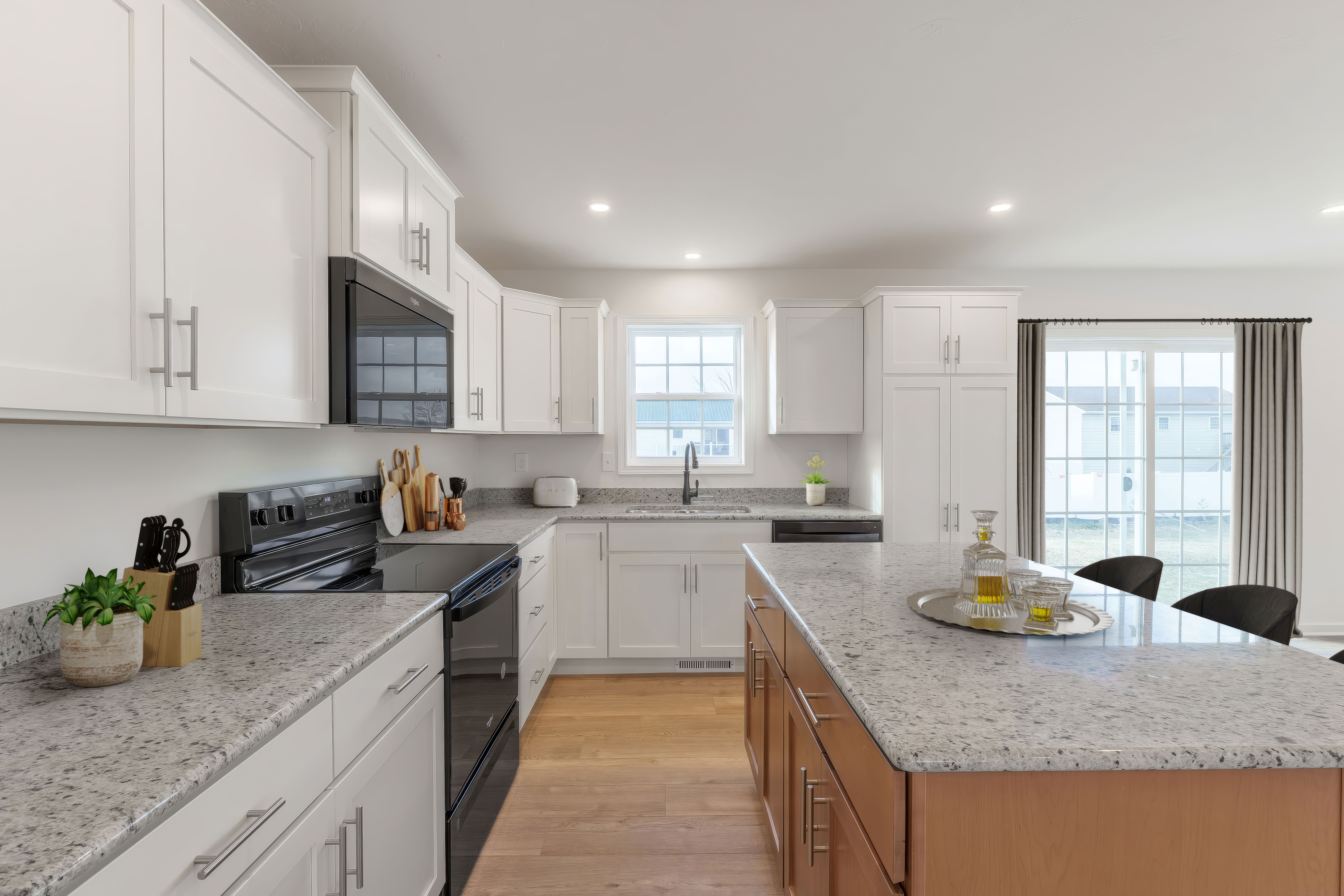 Bright kitchen with white cabinets, granite countertops, center island, and window over sink