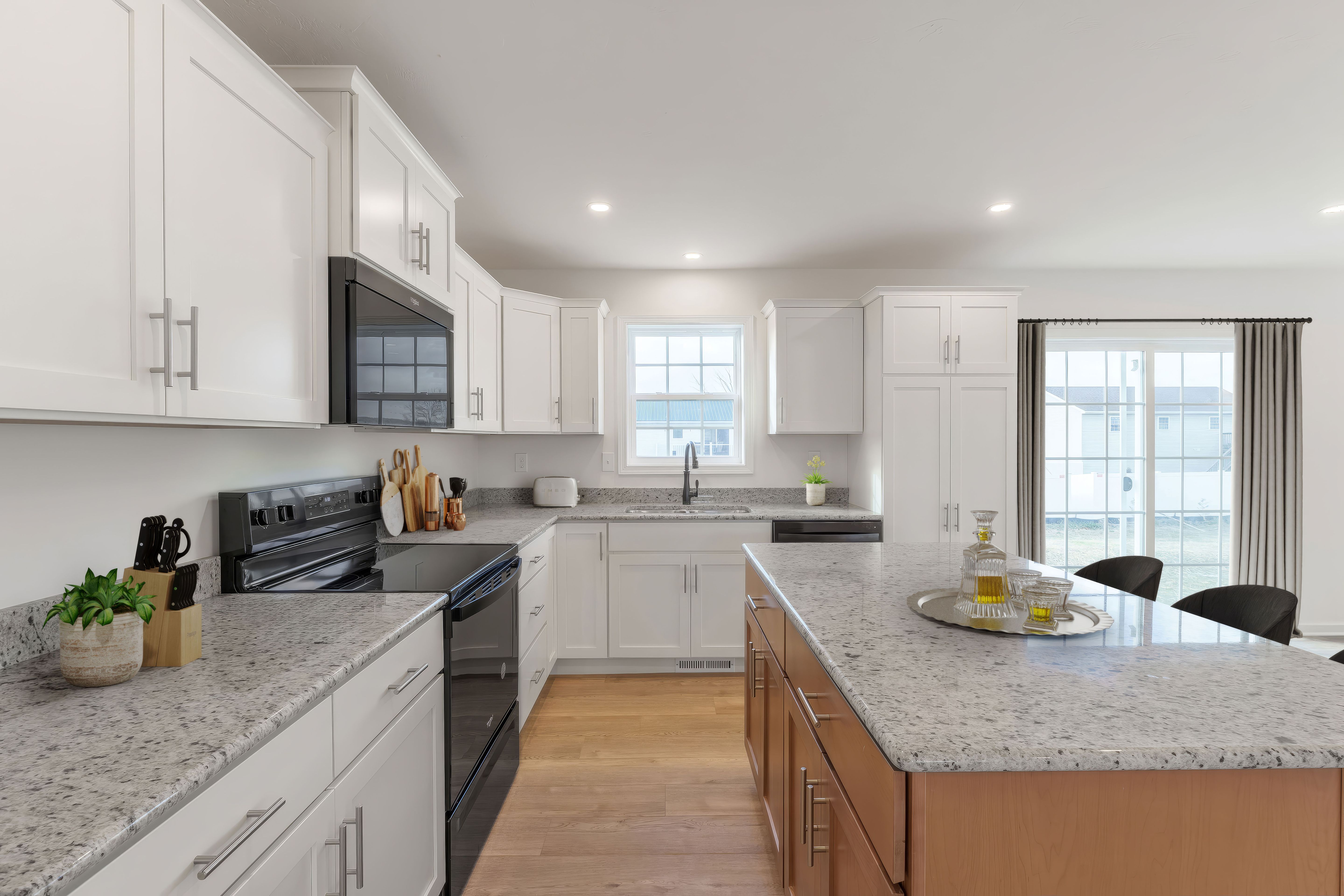 Bright kitchen with white cabinets, granite countertops, center island, and window over sink
