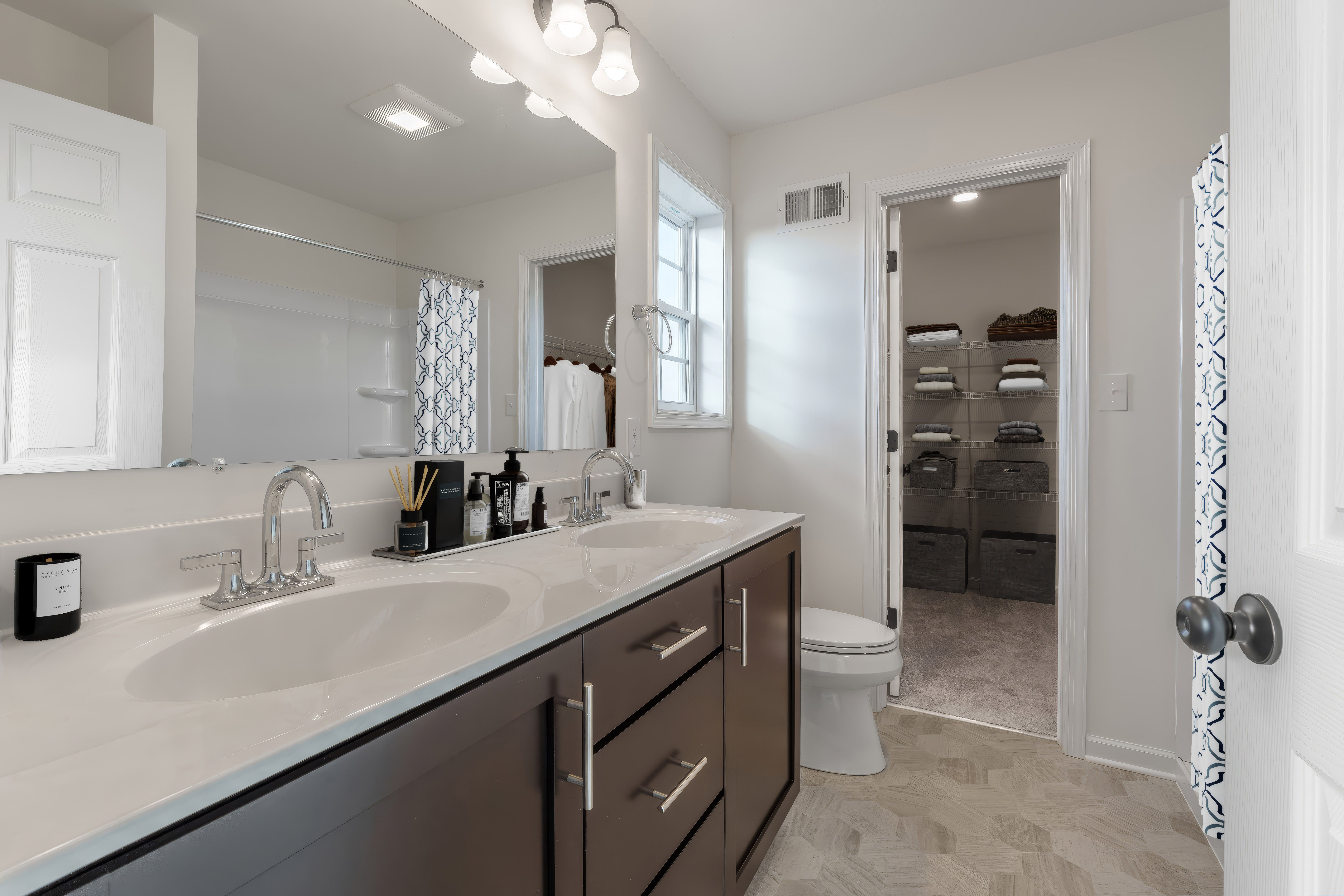 Owners bath with double vanity, large mirror, and walk-in closet access