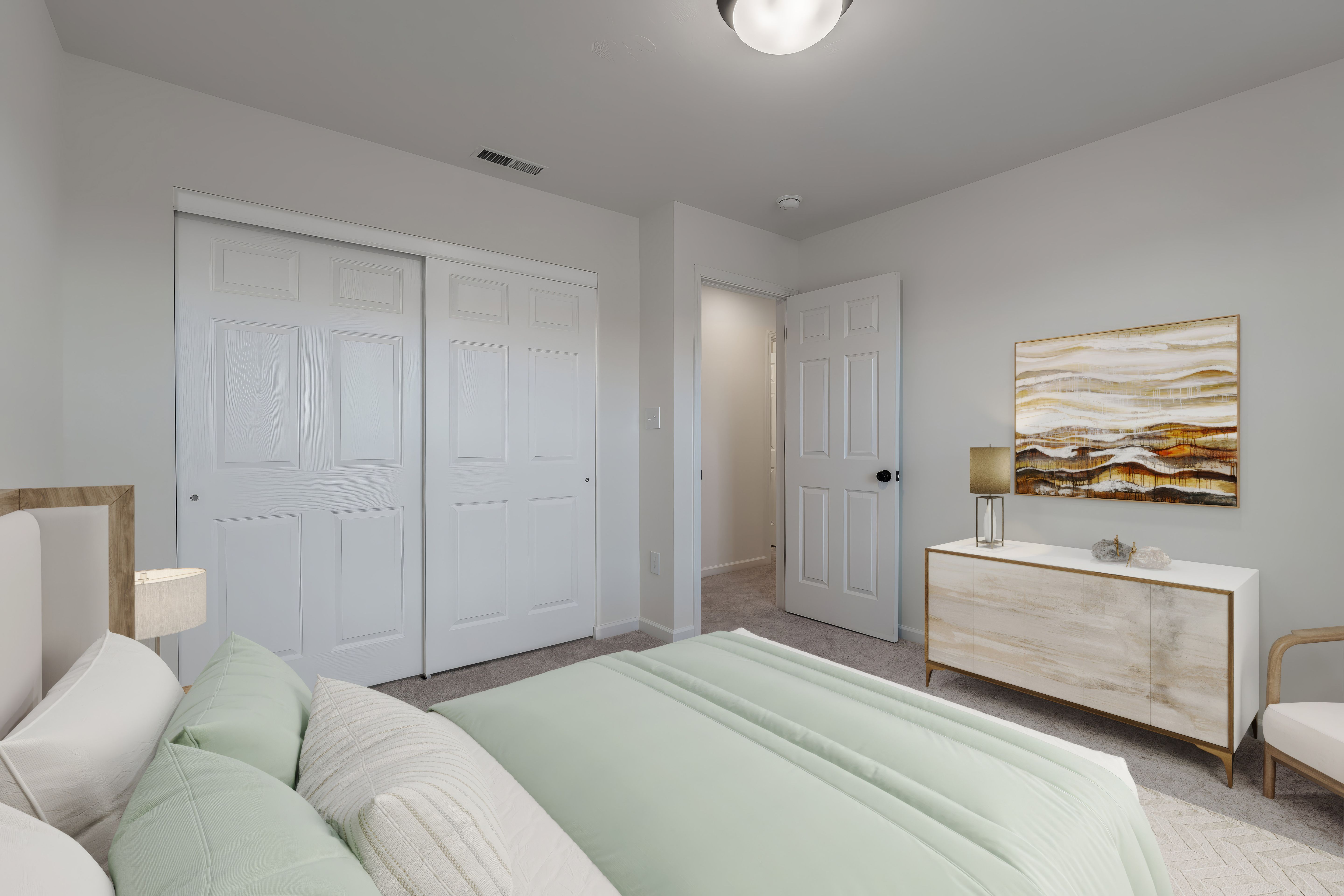 Bedroom view with double closet doors, dresser, and doorway to hall in neutral tones