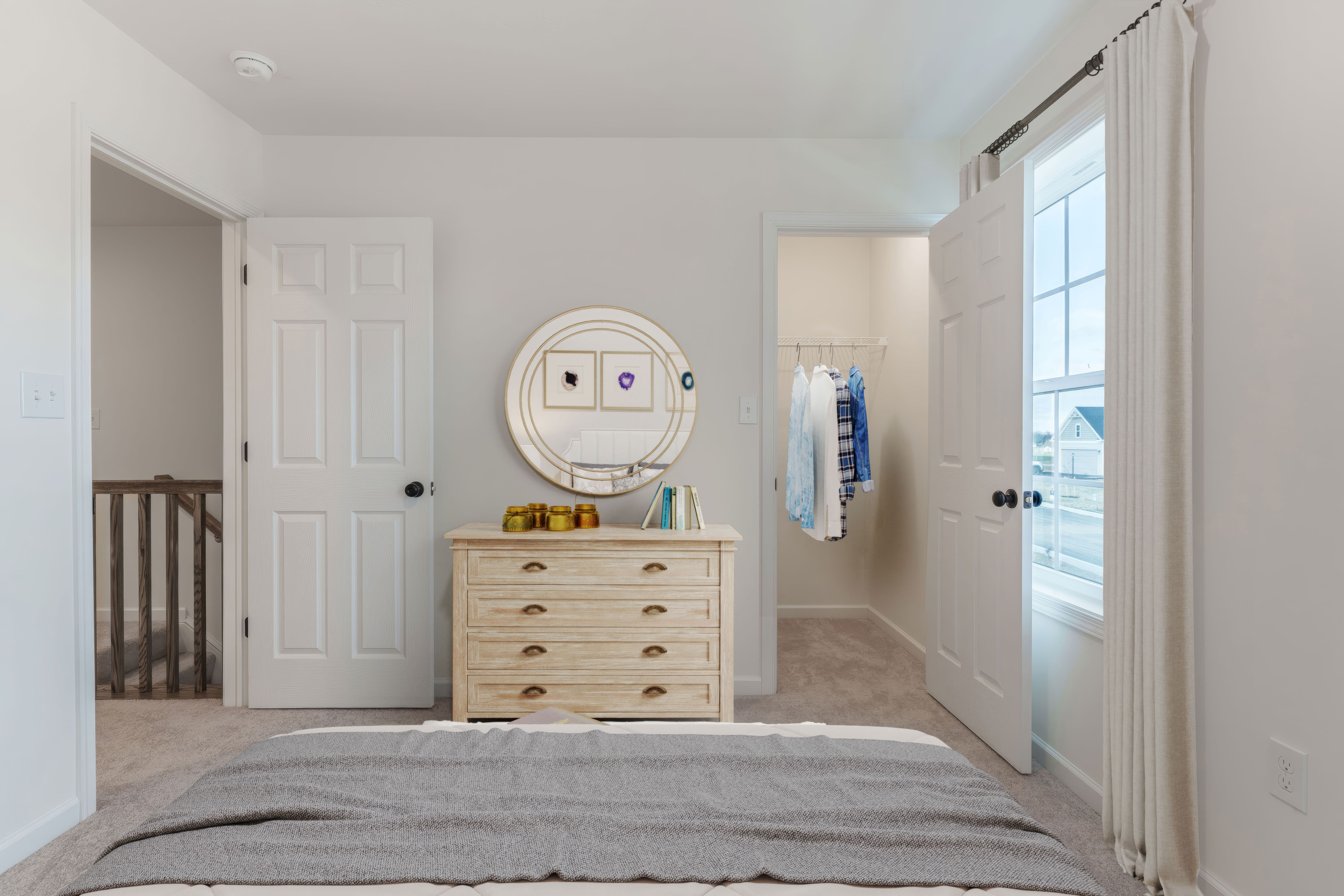 Bedroom with walk-in closet, dresser, and window bringing in natural light
