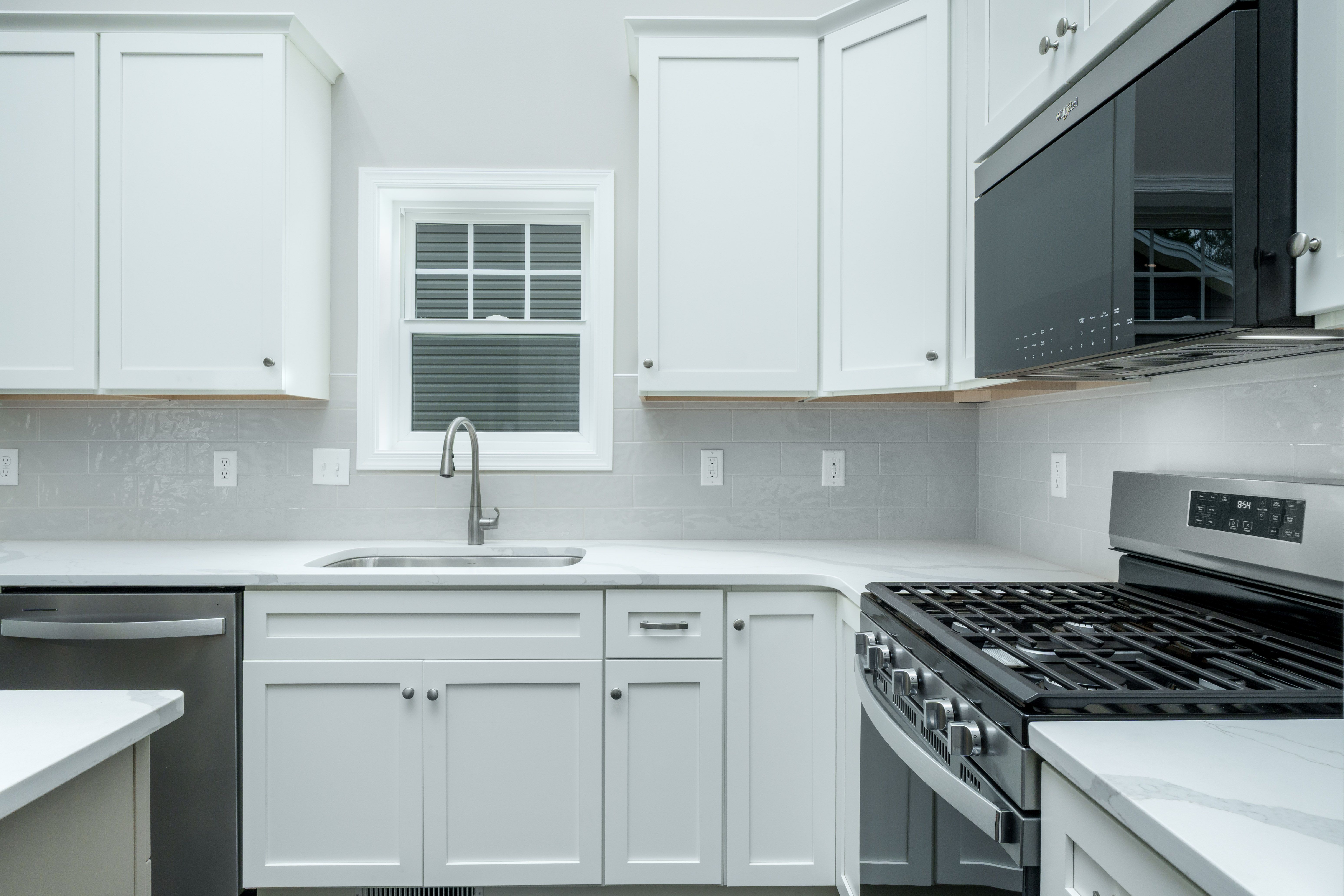 U-shaped kitchen with white cabinets, stainless steel appliances, and tile backsplash
