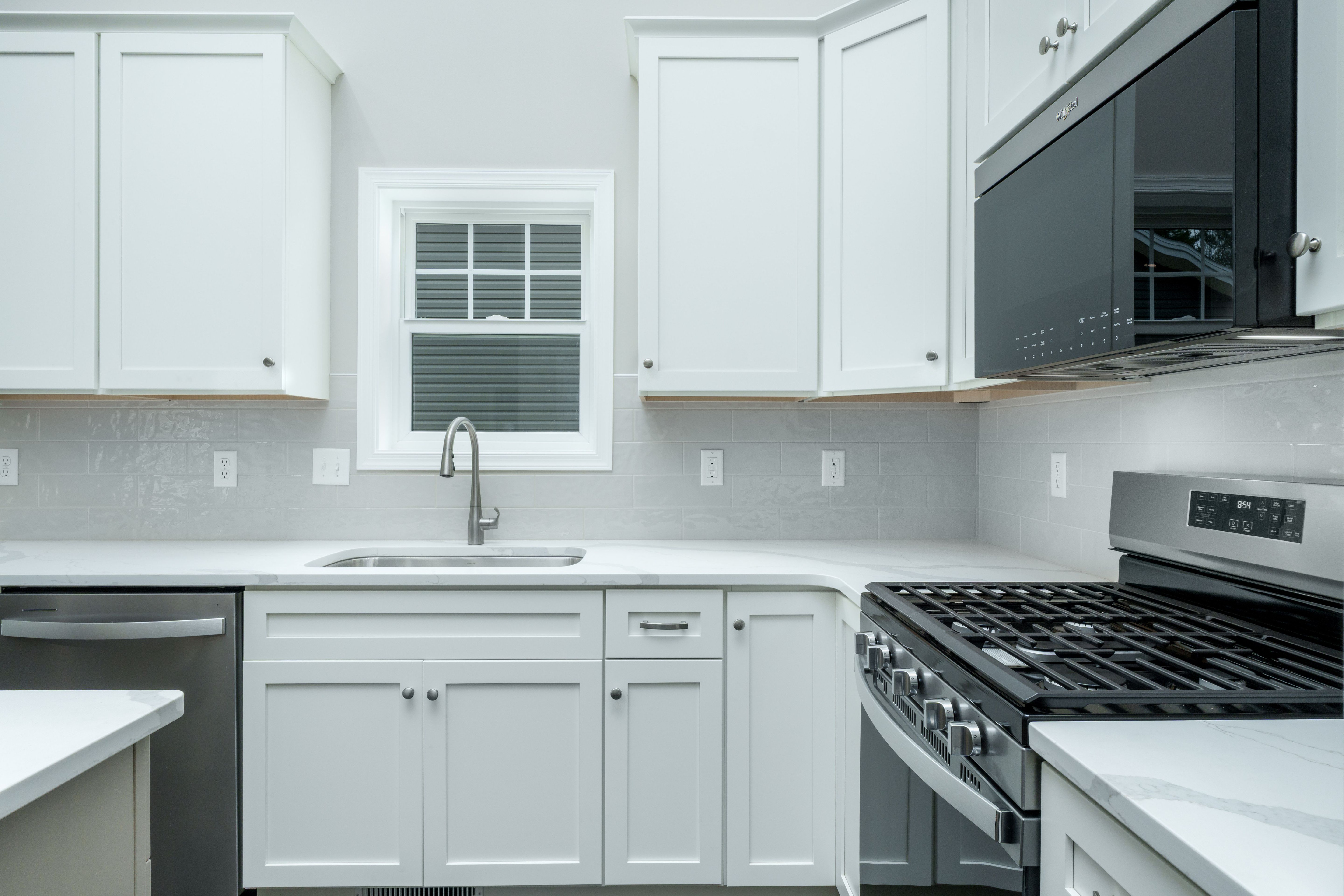 U-shaped kitchen with white cabinets, stainless steel appliances, and tile backsplash
