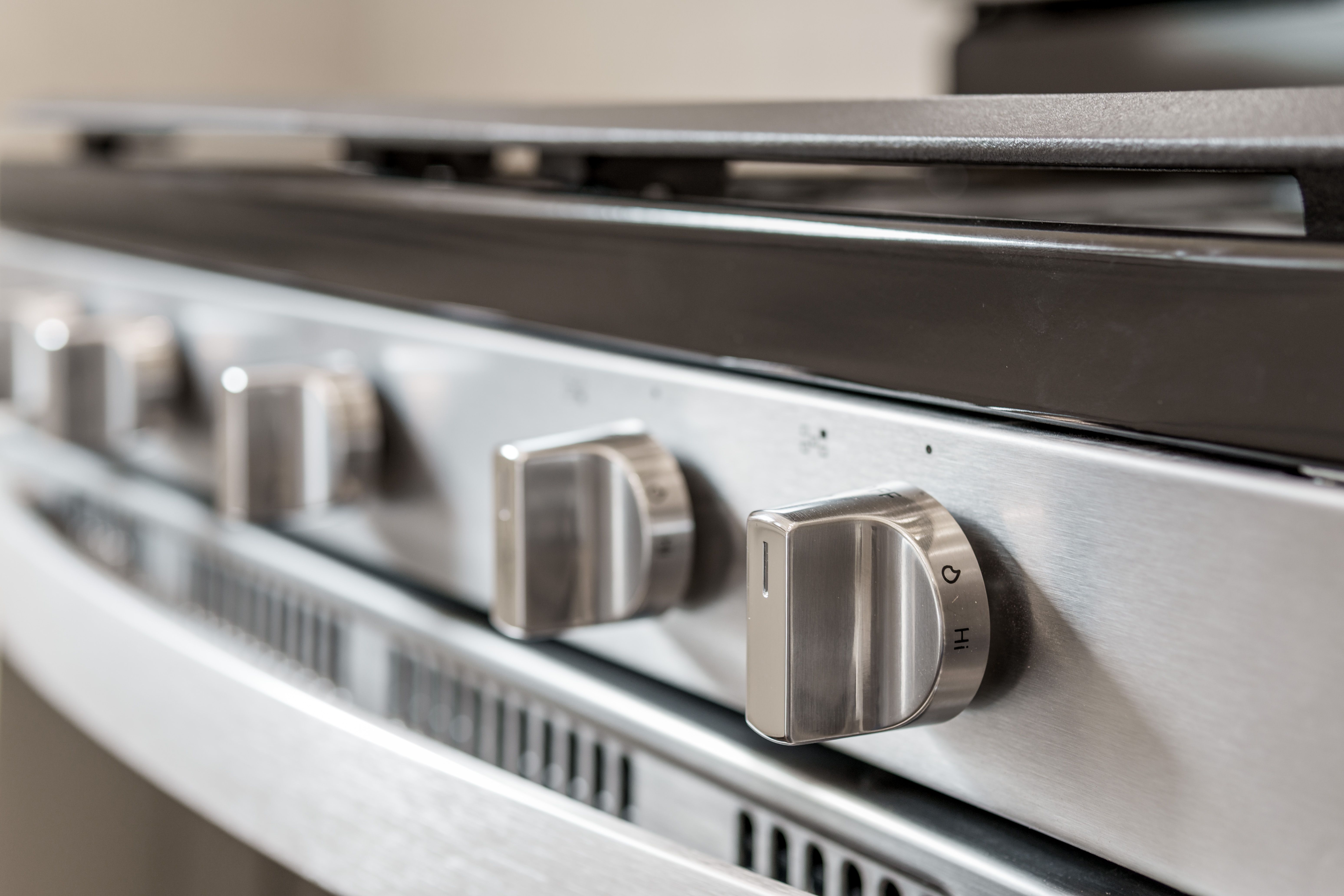 Close-up of stainless steel gas range knobs with modern appliance finish